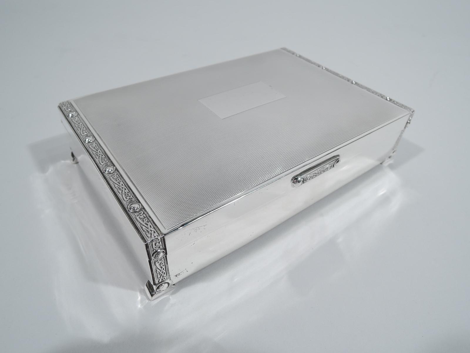 George VI sterling silver box. Made by Charles S. Green & Co. Ltd in Birmingham in 1951. Rectangular with plain and straight sides and bracket supports. Cover hinged; top has central rectangle (vacant) surrounded by engine-turned ornament. At ends