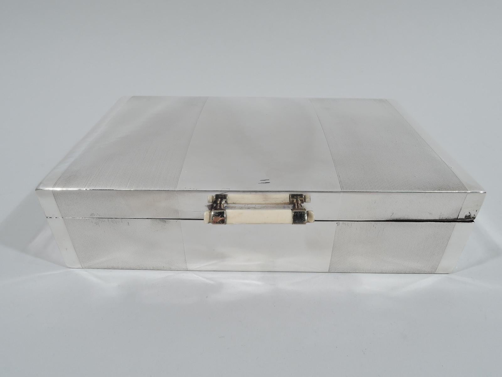 George VI sterling silver box. Made by Mappin & Webb in London in 1938. Rectangular with straight sides. Cover hinged with gently curved top. Plain center between wide bands comprising wraparound engine turned lines. Faceted linear handle in gold