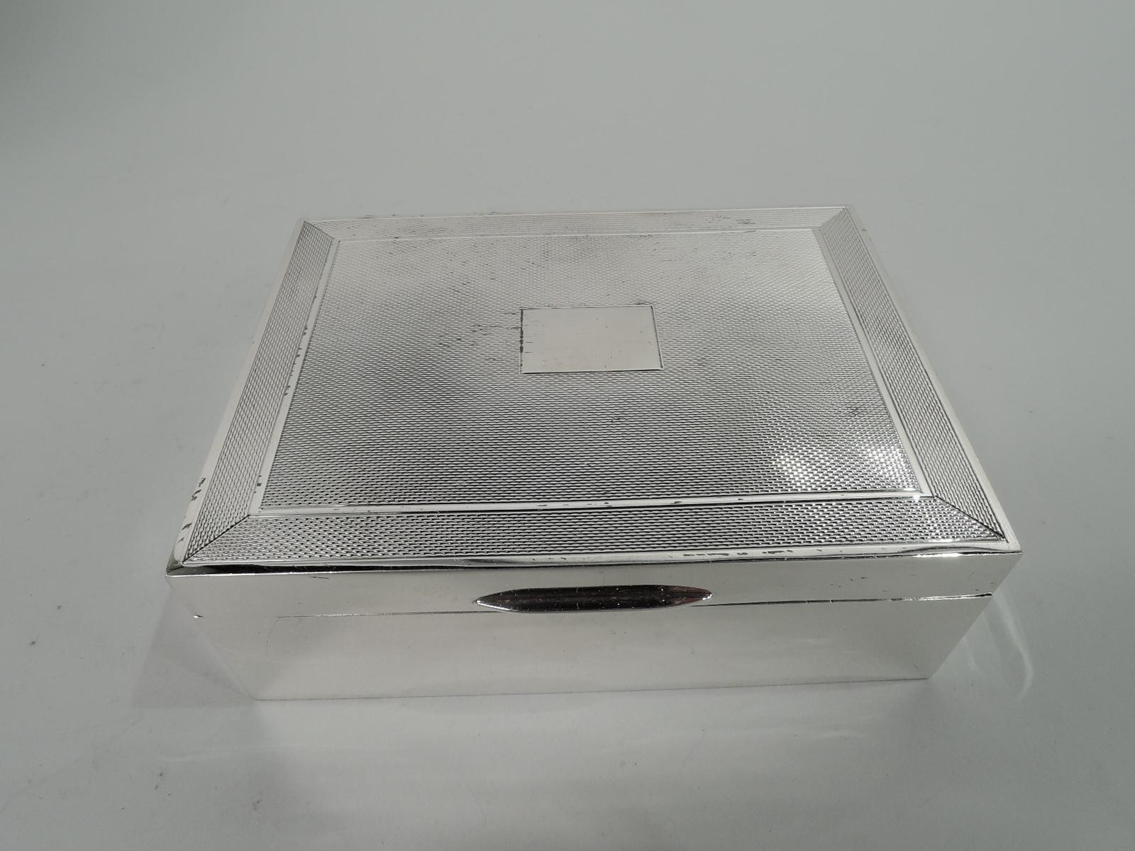 Art Deco sterling silver box. Made by John Rose Birmingham in 1969. Rectangular with plain straight sides. Cover hinged with tapering tab. Cover top has central mono plate (vacant) surrounded by engine-turned ornament and same border in plain