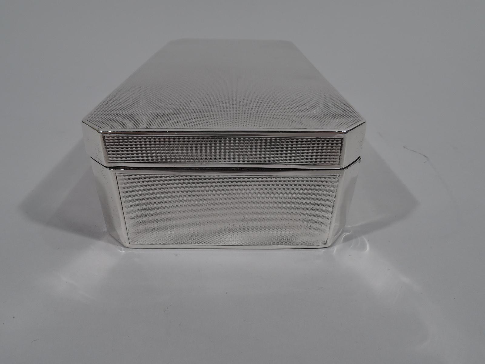 George V sterling silver desk box. Made by John Rose in Birmingham in 1938. Rectangular with chamfered corners and hinged and tabbed cover. All-over engine-turned wave ornament except for rectangular mono plate (vacant) on box front and corners. Box