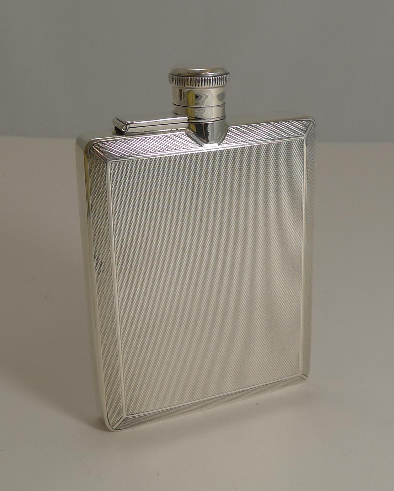 A very striking and smart sterling silver hip flask with an all-over engine-turned decoration to both the back and front.

The hinged lid requires a twist and lift action and reveals the cork within the lid to keep the precious contents.

The