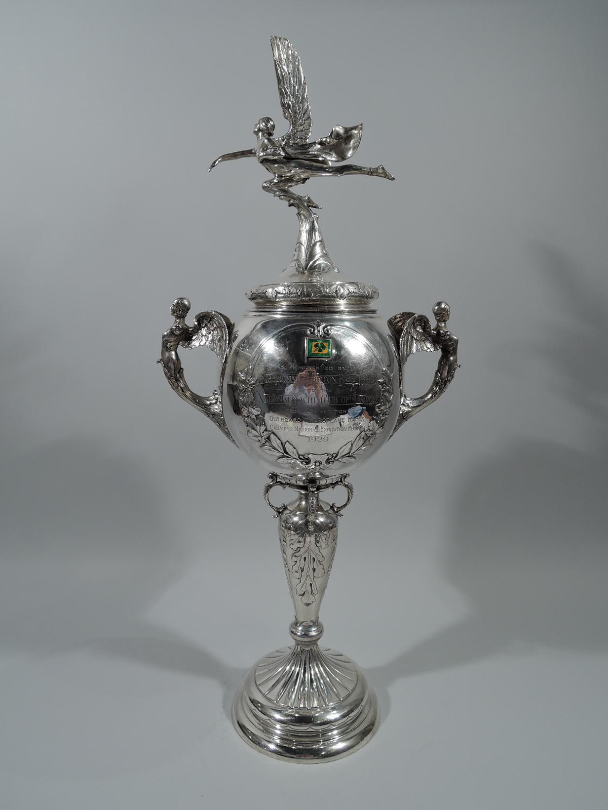 George V sterling silver trophy cup. Made by Goldsmiths & Silversmiths in London in 1929.

Bowl with wing-mounted and leaf-wrapped caryatid side handles. Applied enamel flags and circular and wreathed frames. One is inset with a chased motorboat in