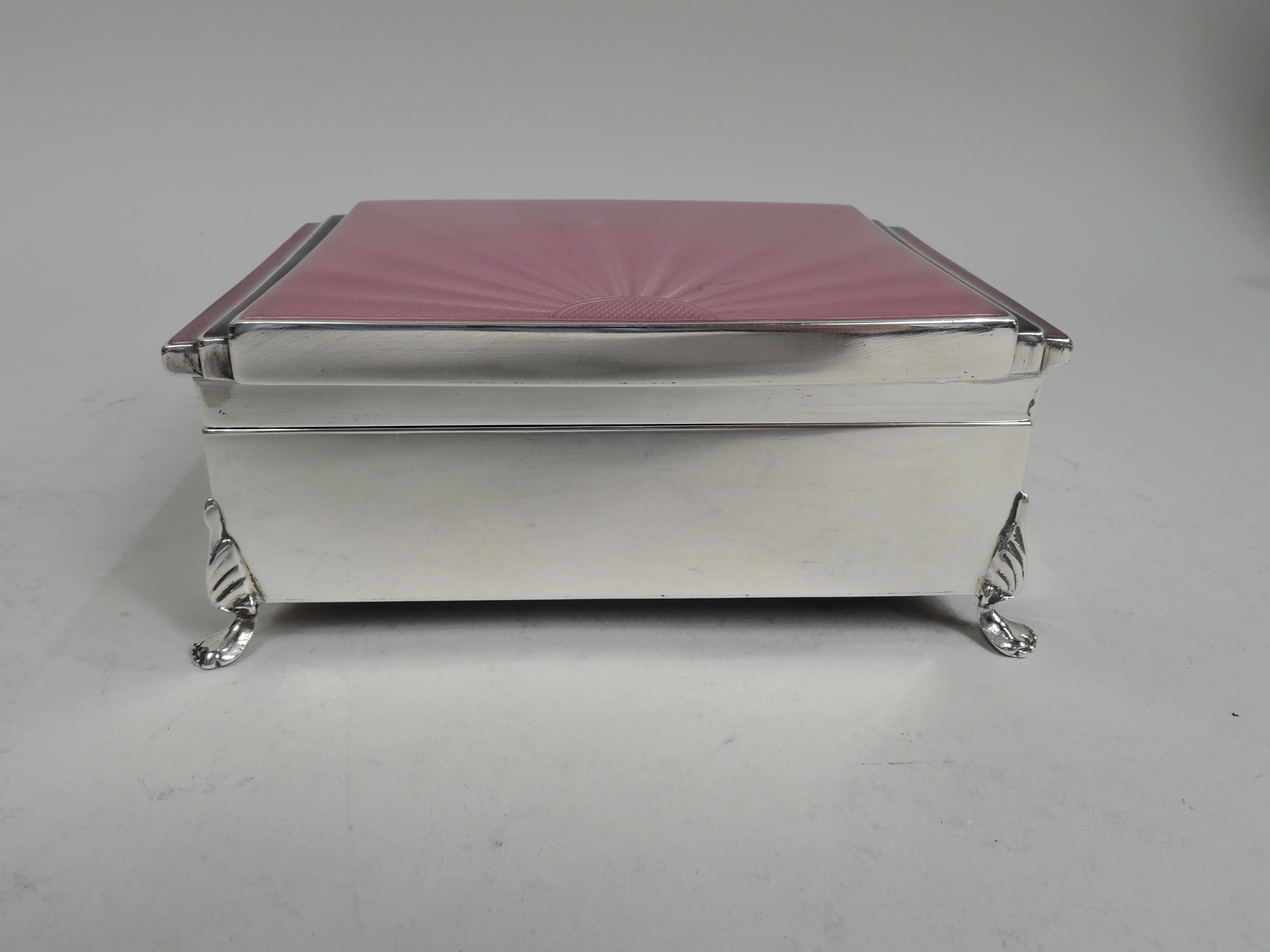 George V sterling silver box. Made by Henry Clifford Davis in Chester in 1935. Rectangular with straight sides and stylized leaf-mounted paw supports. Cover hinged, flat, and overhanging with pink radiating guilloche enamel and stepped sides in