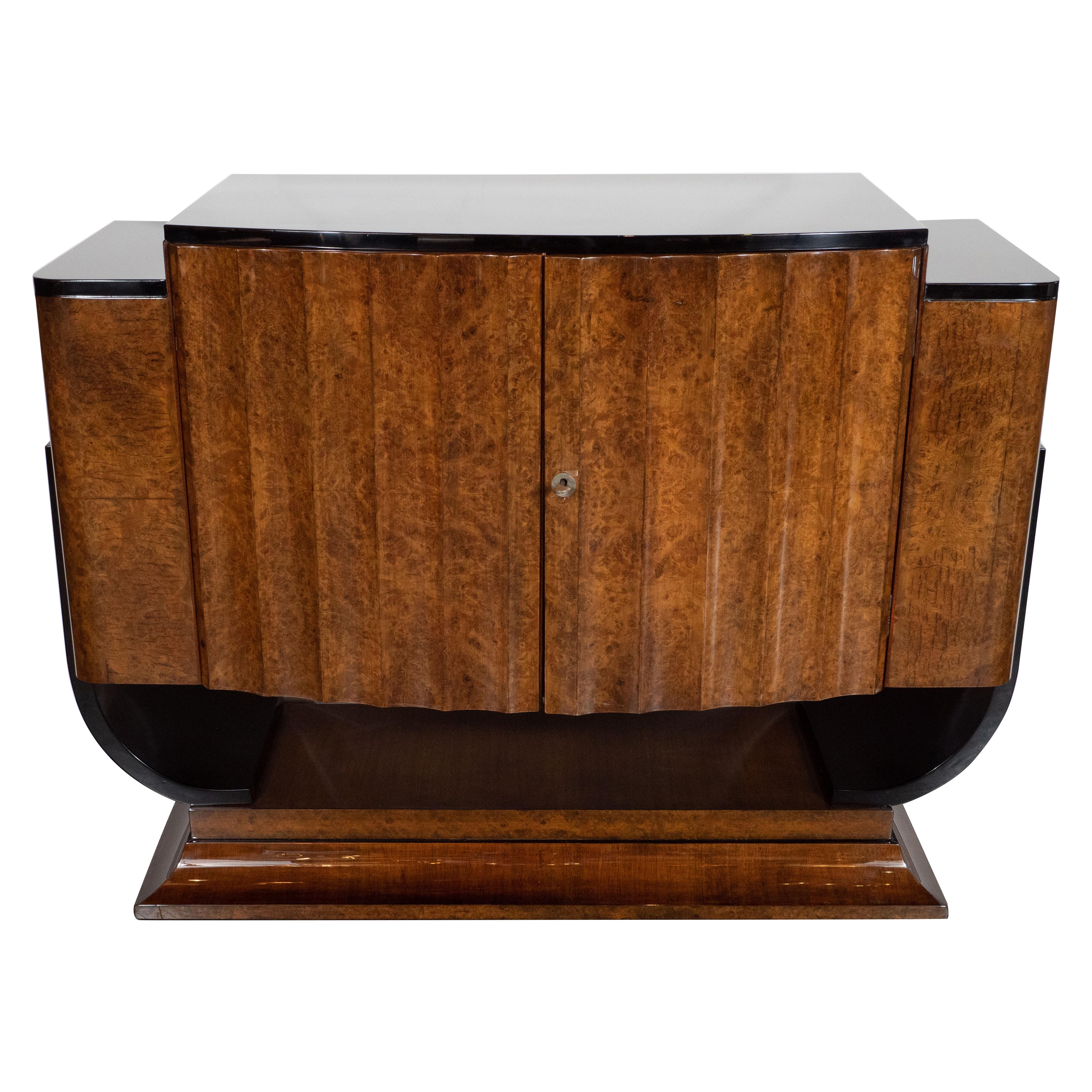 This stunning Art Deco cabinet was realized in the United Kingdom, circa 1930. It features a plinth style concave tiered rectangular base with black lacquer detailing that ascends into two U-form streamlined supports also in black lacquer. The