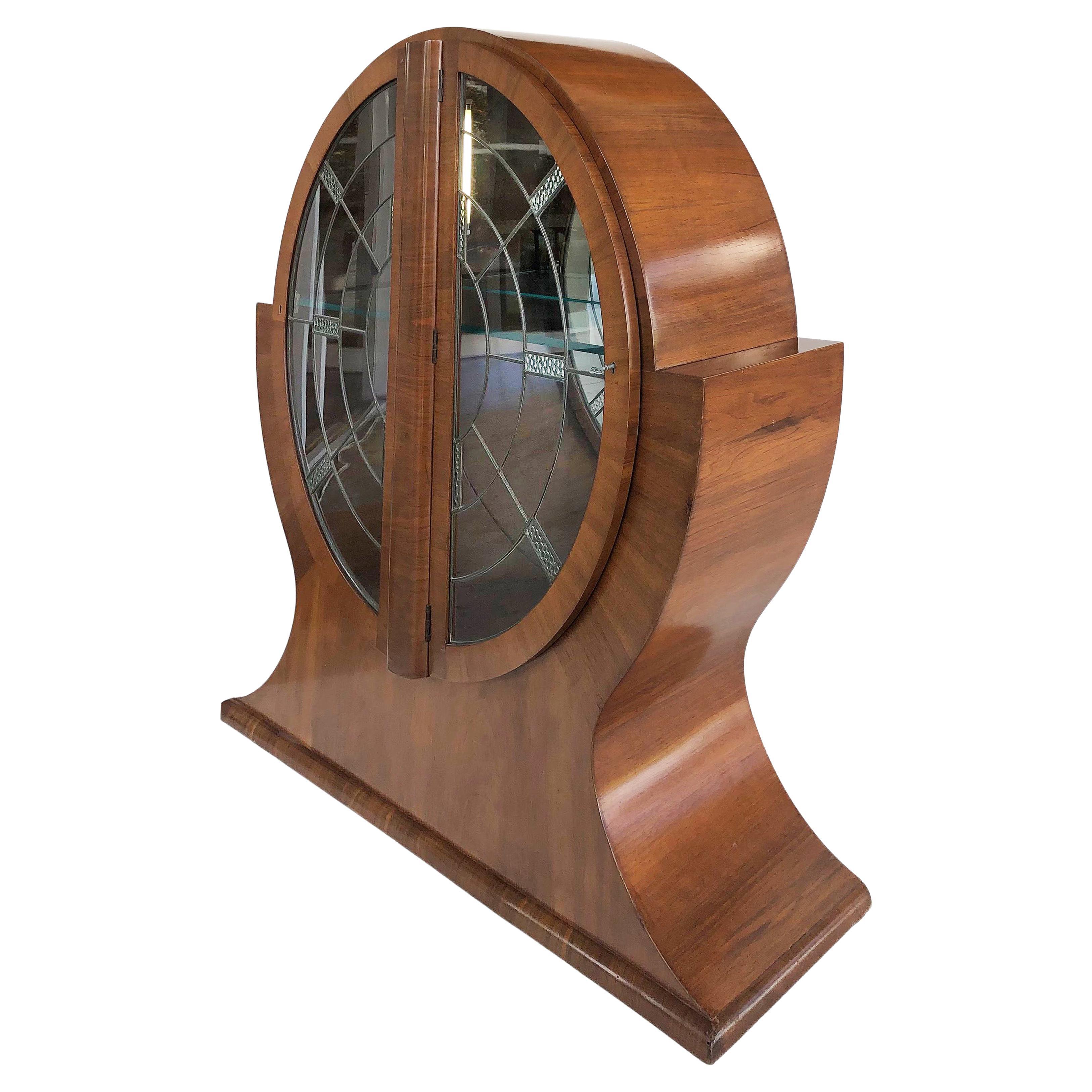 English Art Deco walnut and glass display cabinet vitrine, 1930s

Offered for sale is an Art Deco walnut and glass circular display cabinet vitrine from England dating to the 1930s. This cabinet has two beautifully decorated leaded glass doors