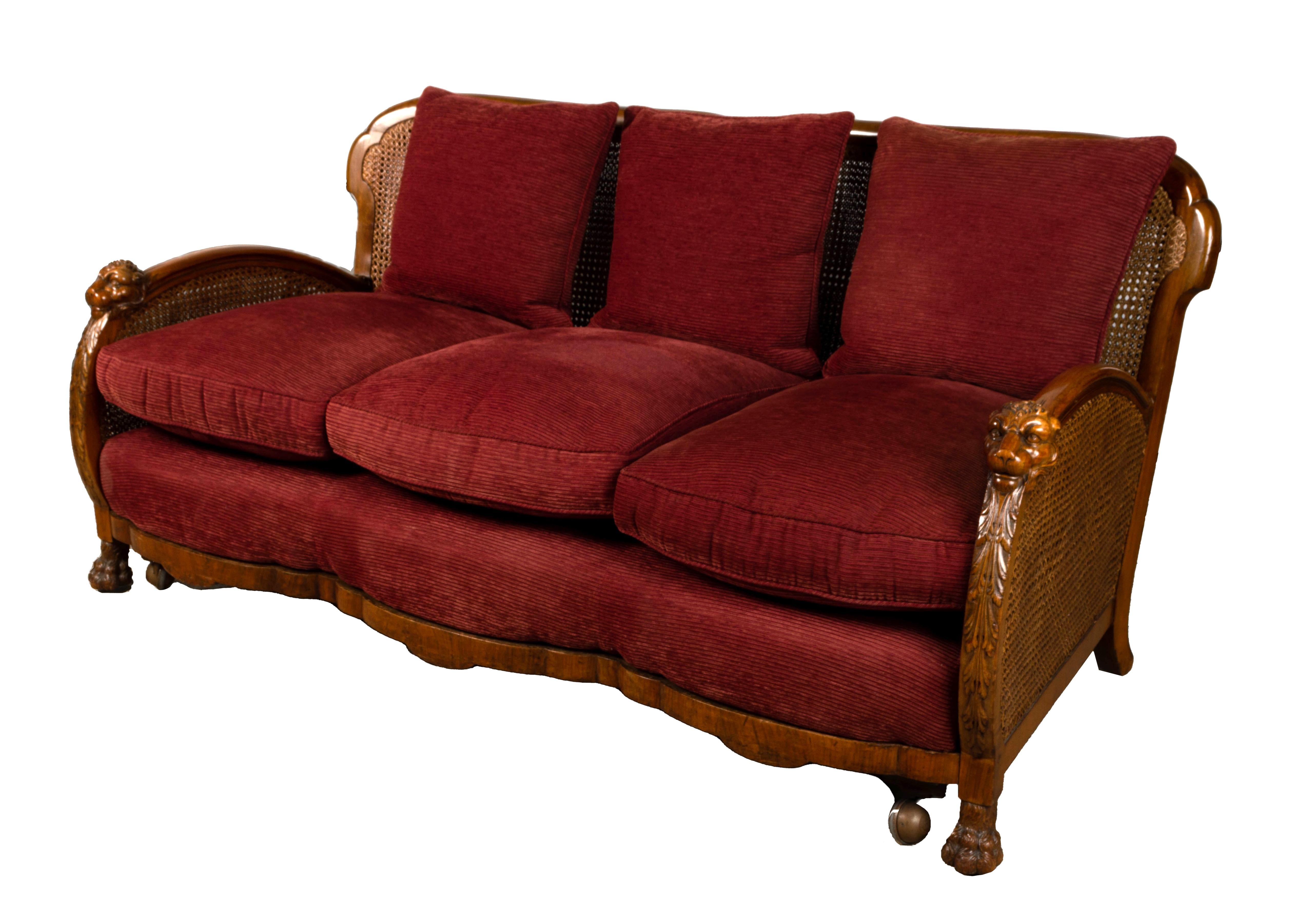 An English Art Deco Walnut Framed Bergere Sofa C.1920. 

Classic Art Deco shaped arms with with acanthus leaf and lion head carvings.
A scalloped apron terminating on ball and claw feet. The sofa has additional castors for ease of movement (these