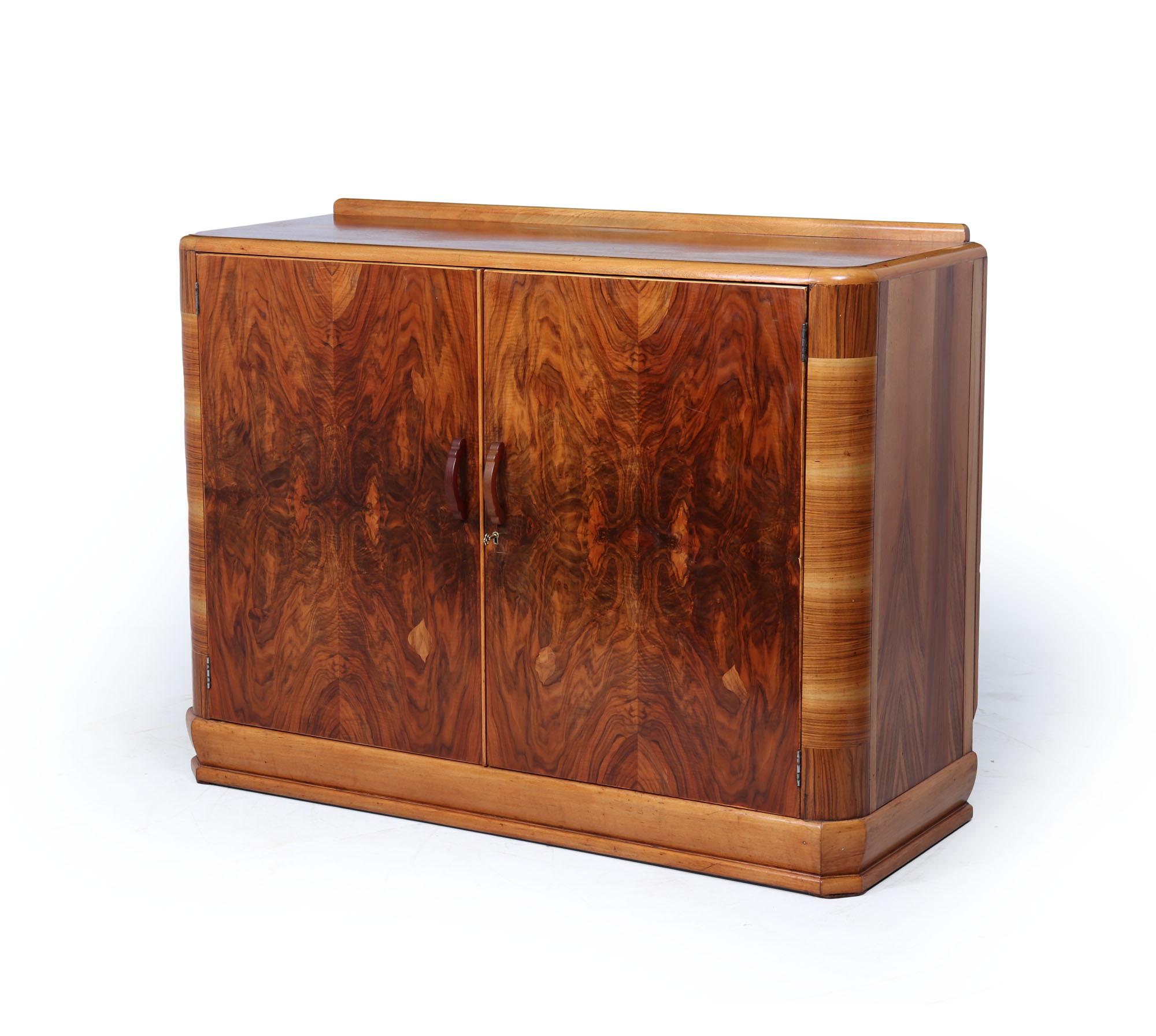 Art Deco Sideboard 
An elegant English Art Deco sideboard from the 1930s, featuring highly figured walnut veneers with beautifully bookmatched grain across the twin doors. The sides are gently curved, and the stepped plinth base and rounded top