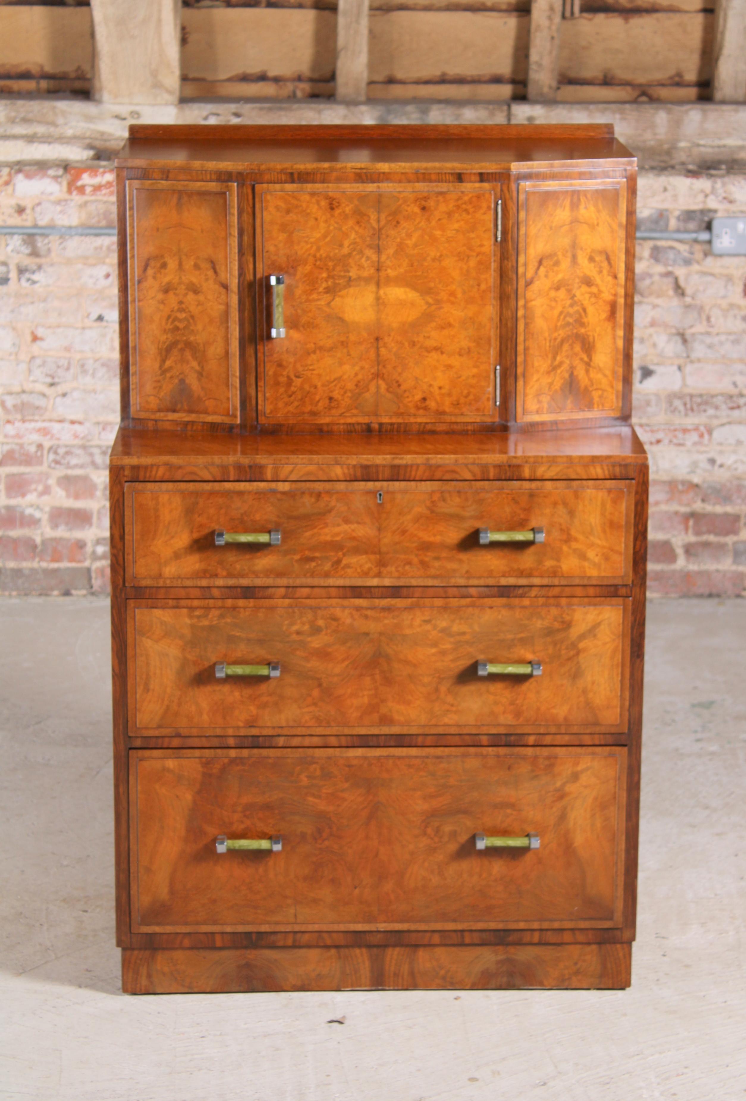 Art Deco walnut tallboy/cabinet, circa 1930s. 3 drawers and a cubpoard section with chrome and green bakelite handles. 

Measures: W 76cm
D 51cm
H 123cm.