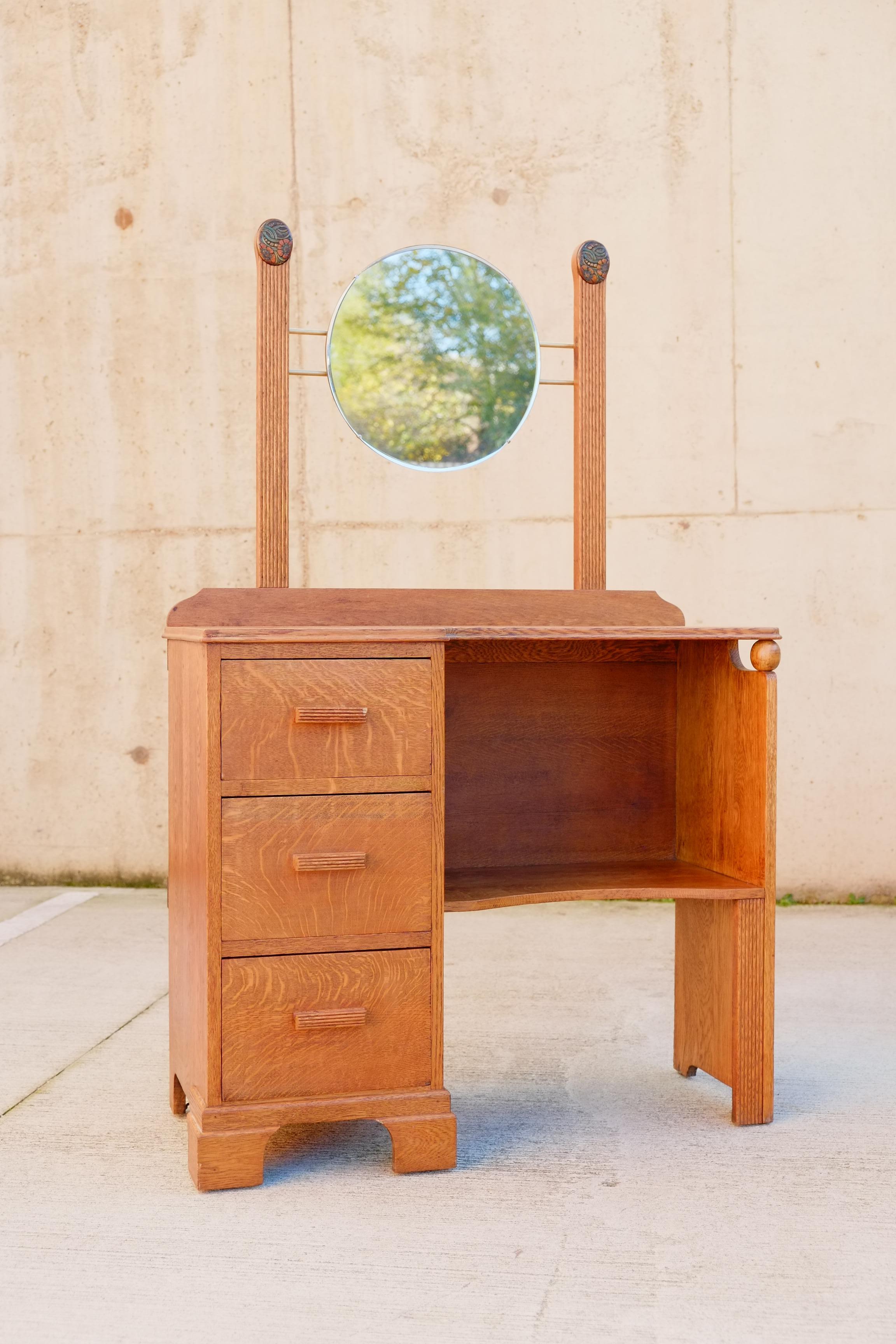 A beautiful 1930s Art Nouveau dressing table from England. This vanity has three deep drawers to the left side with an open seating space and shelf to the right. The vanity is made of solid oak with the most beautiful reeded and hand carved details.