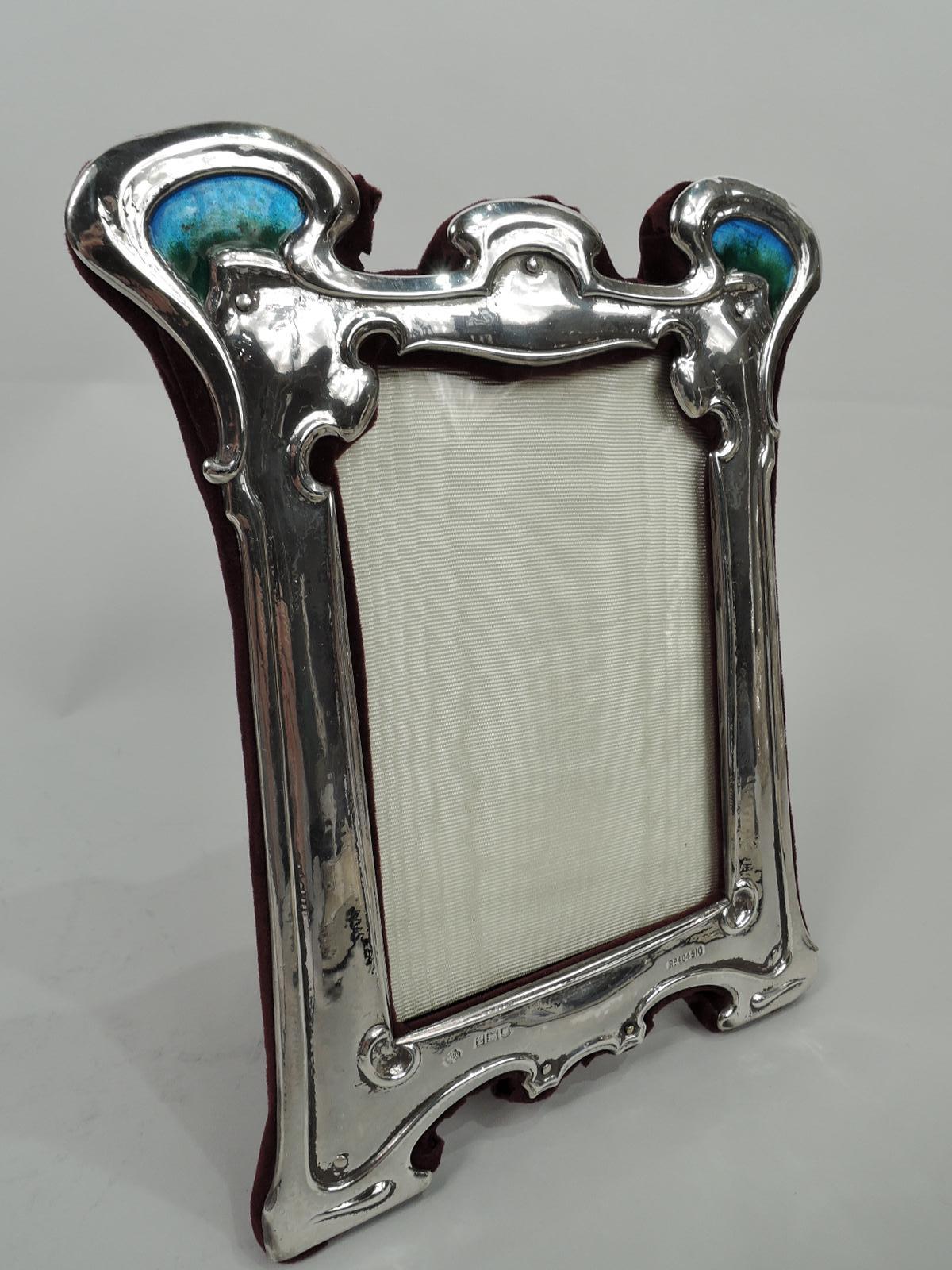 Edwardian Art Nouveau Liberty-style sterling silver picture frame. Made by William Hutton & Sons in London in 1902. Rectangular window with shaped upper corners in curvilinear surround with bracket supports. Top corners have scrolled tendrils inset
