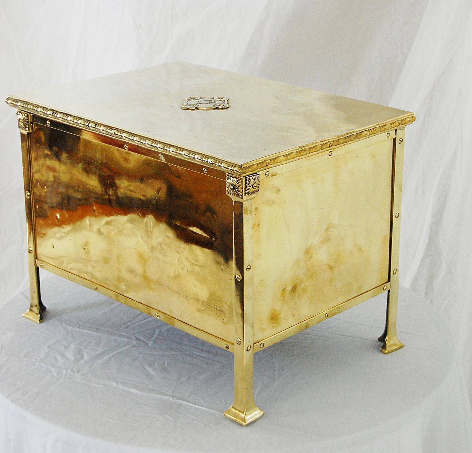 English Art Nouveau period brass log bin with hinged lid. This log bin has the high quality construction technique of overlaying the brass onto iron or wood. In this case the brass lid is overlaid on an iron base, while the base of the bin is