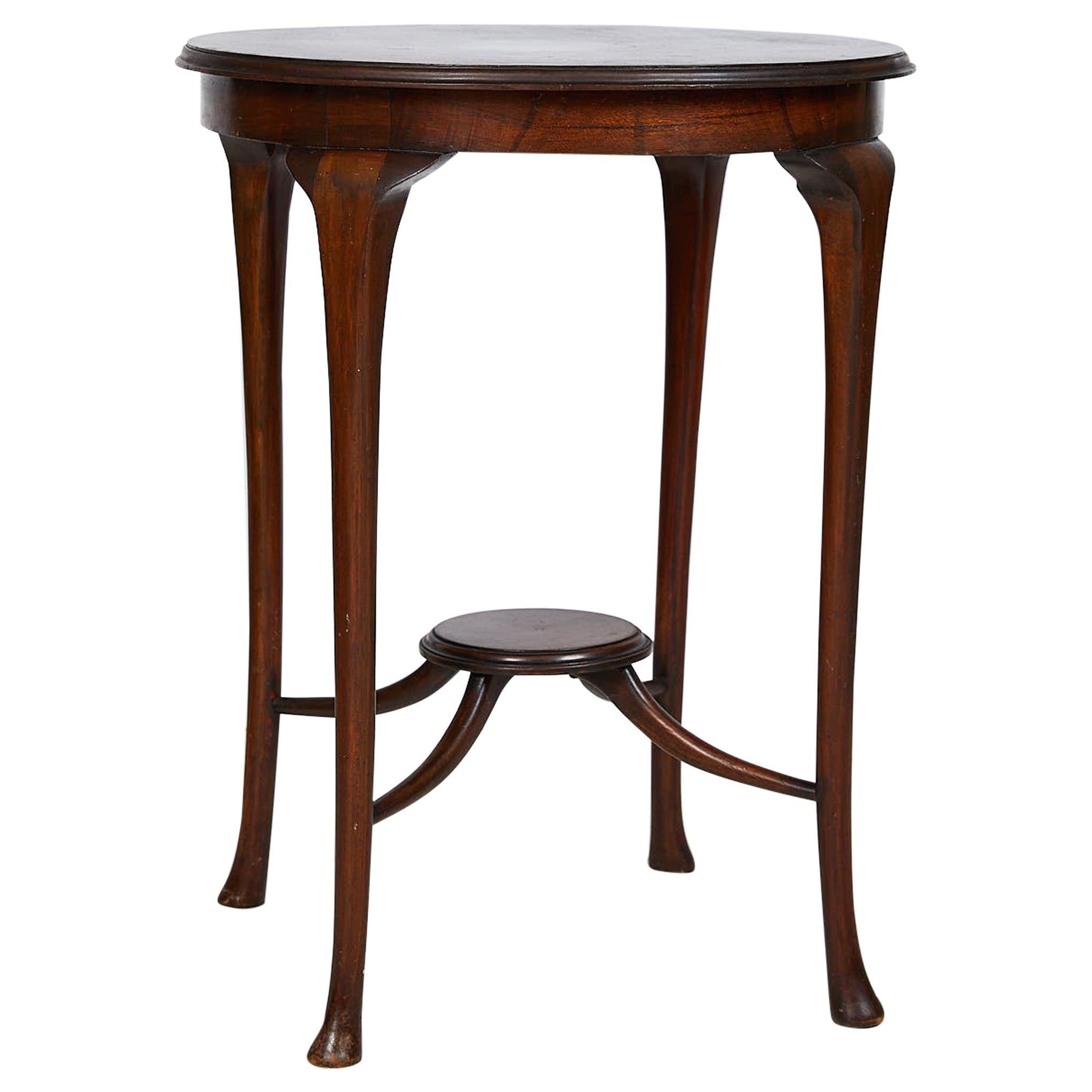 Early 20th century elegant English tea or side table made of mahogany during the Art Nouveau period. The upper surface, round in shape, has been edged with a delicate and refined molding. There is a second comfortable support surface, also round, in