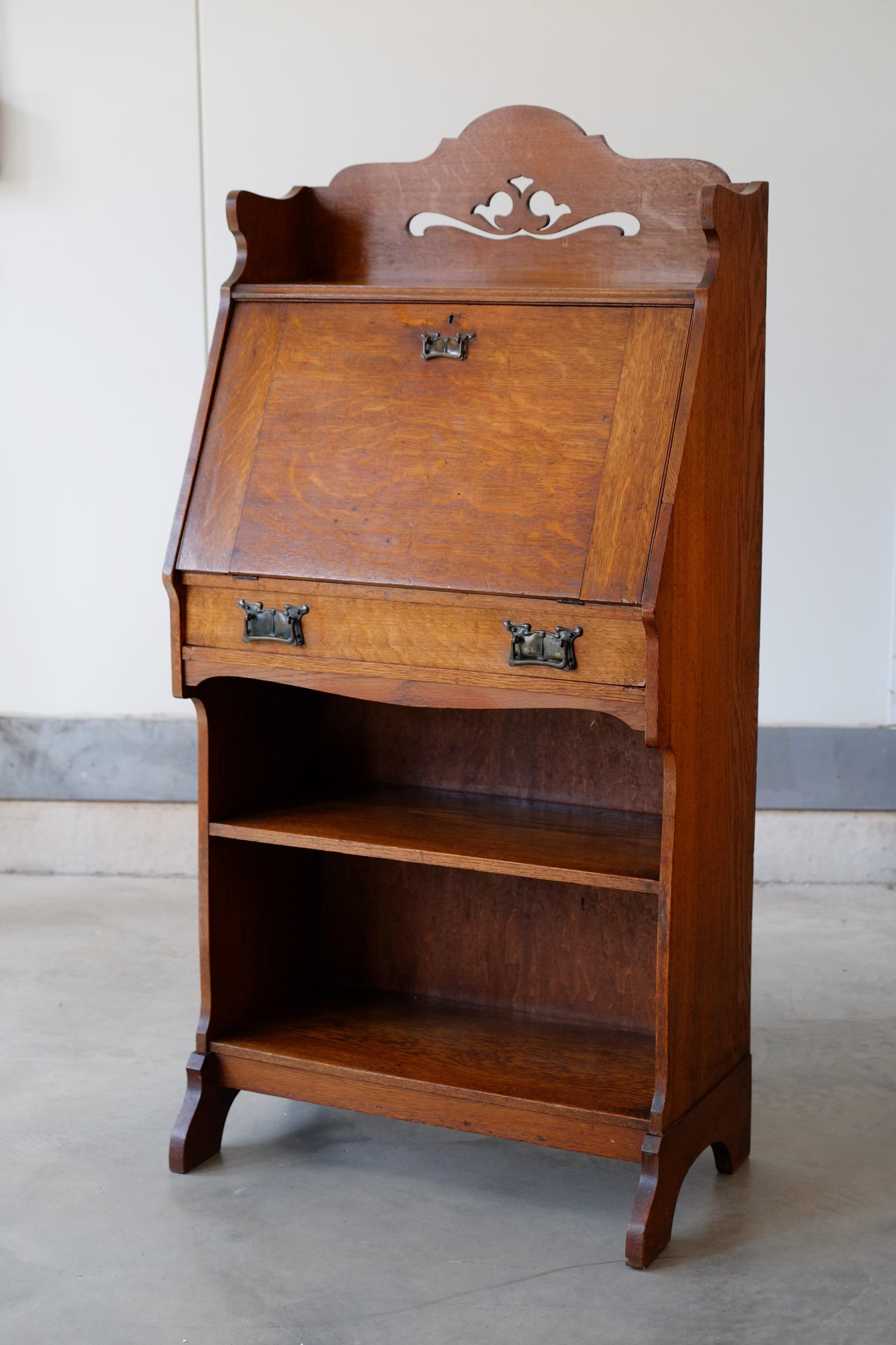 Stunning English Art Nouveau oak cabinet with bureaux. Beautiful design with shapely leg details and beautiful cut work. Beautiful brass plate handles with a classic Art Nouveau pattern. Inside the writing table there are a host of small
