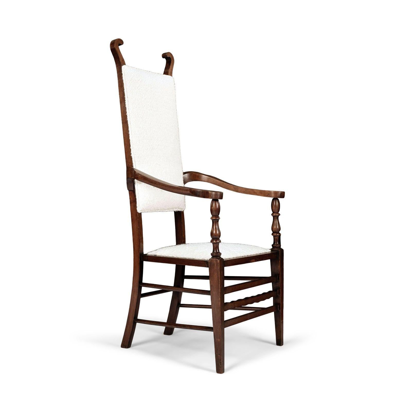 English arts and crafts brown walnut armchair, attributed to JS Henry circa 1900. Scrolled terminals atop a solid back and seat newly upholstered in off-white boucle. Flanked by outswept arms supported by turned uprights. Carved wavy front