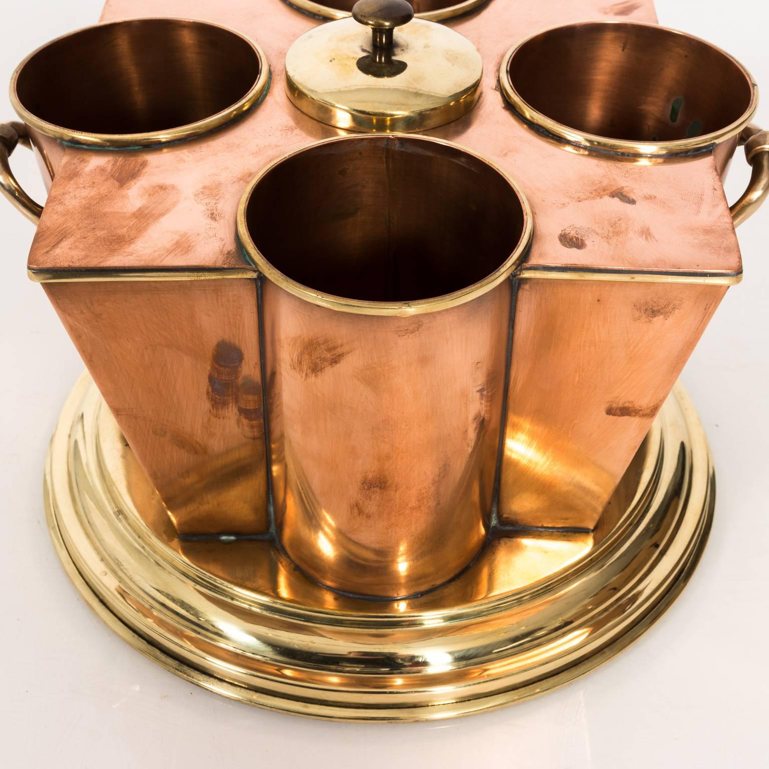 Arts & Crafts English copper and brass wine cooler with five compartments on a round base in a polished finish, circa 1910.
 