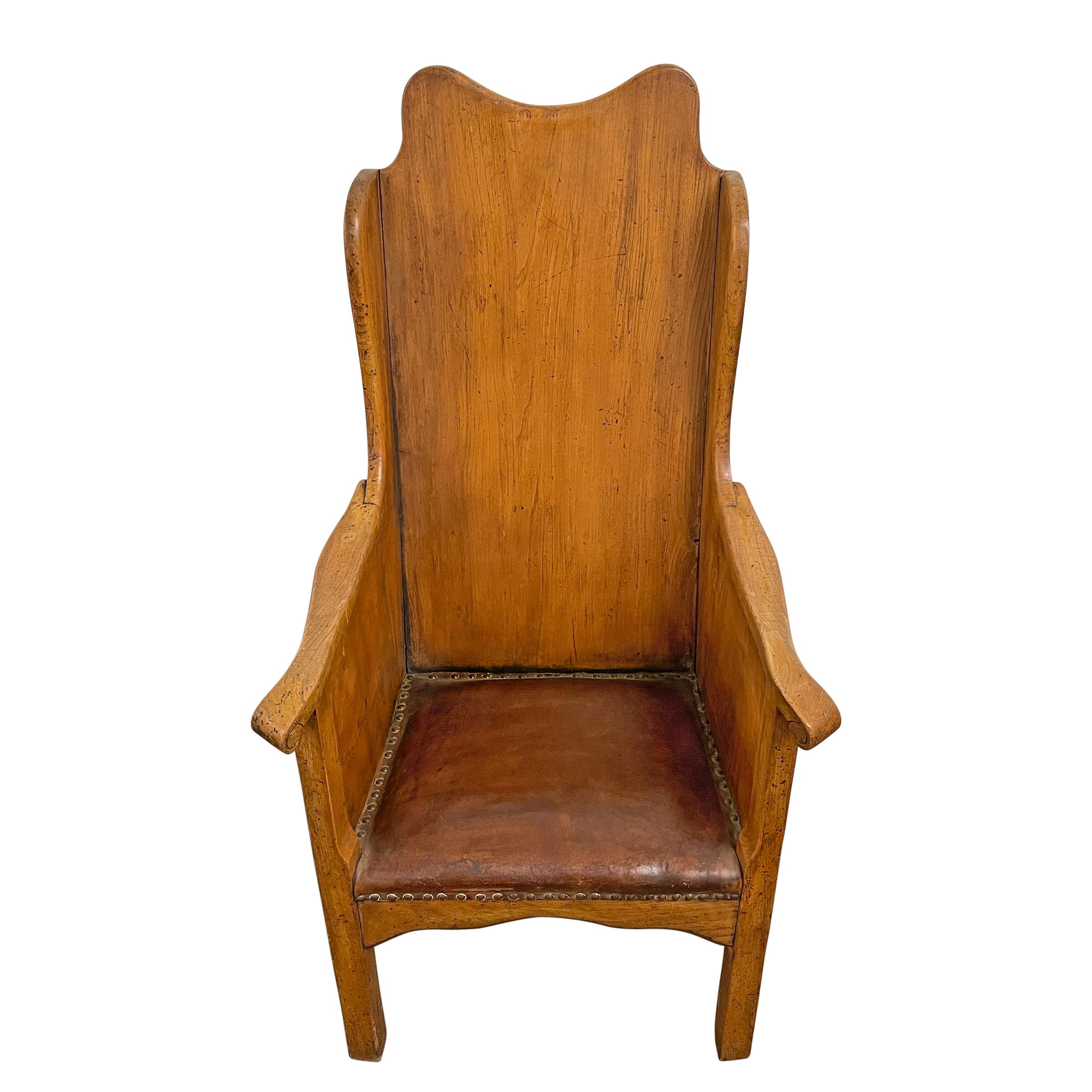 A wonderful late 19th century English Arts & Crafts hall chair with short wings, a scrolled top, out-turned sloping arms, and retaining its original leather upholstered seat with brass nailhead trim.