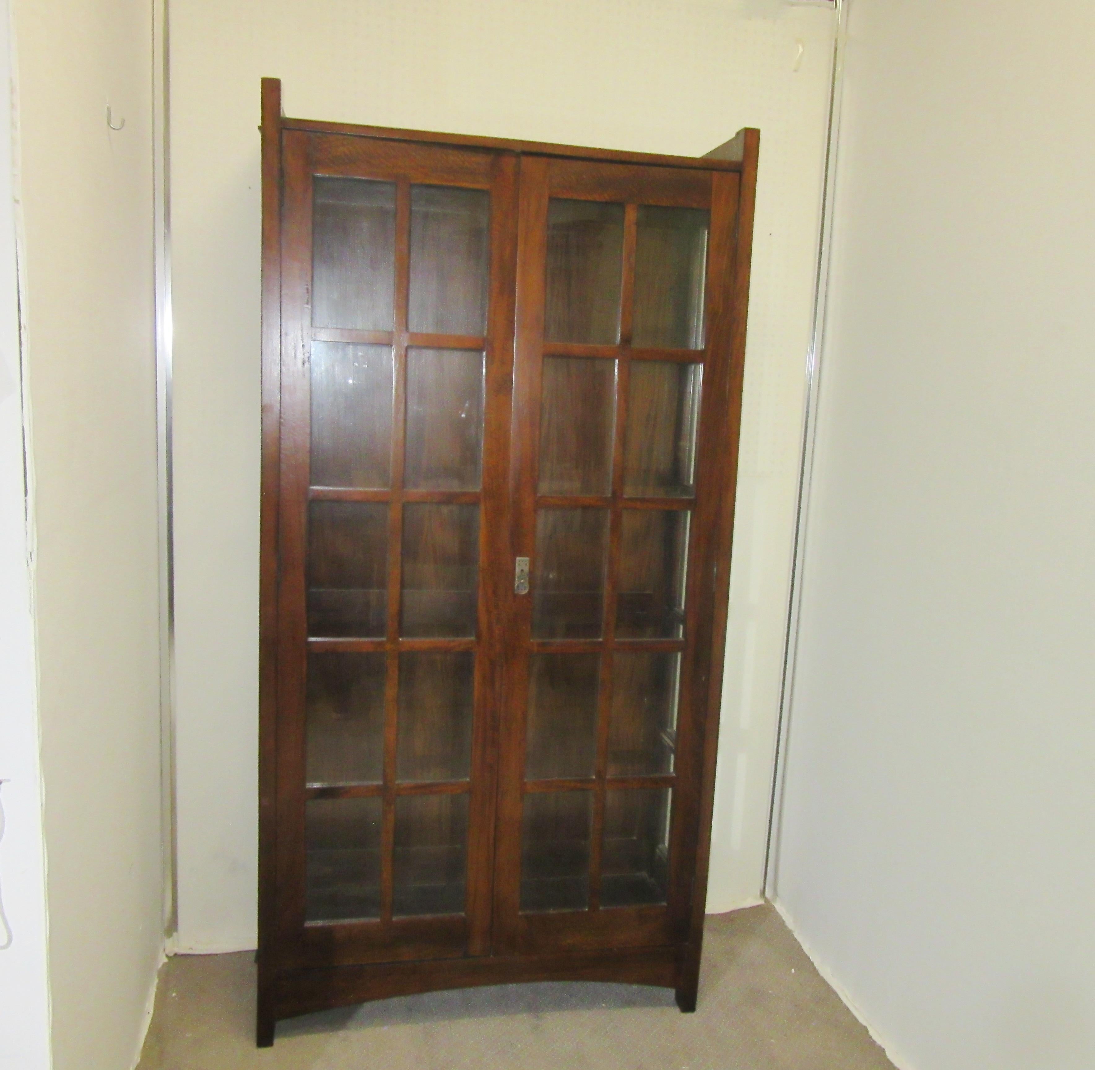 English Arts & Crafts mahogany bookcase. The piece has forty individual panes of glass; twenty in the front and ten on each side. There are a total of five wood shelves on the interior for storage. Made in the 1910s in England, the piece is in great