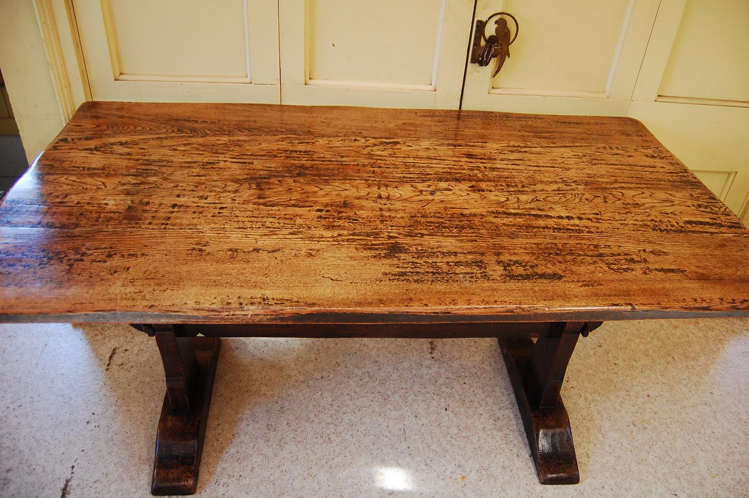  English Arts and Crafts period oak farmhouse trestle table.  This trestle table shows the care and craftsmanship that is a hallmark of the arts and crafts movement.  The top is made of thick oak planks, hand riven; the base is beautifully  hand