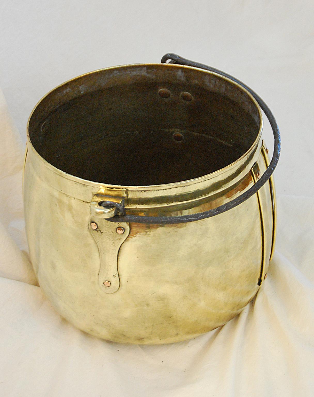 English 19th century Arts & Crafts period brass 15 1/2 inch cauldron with iron swing handle. This exceptionally heavy quality brass cauldron exemplifies the Arts & Crafts period with enhanced decorative extensions to the bold handle carriers and