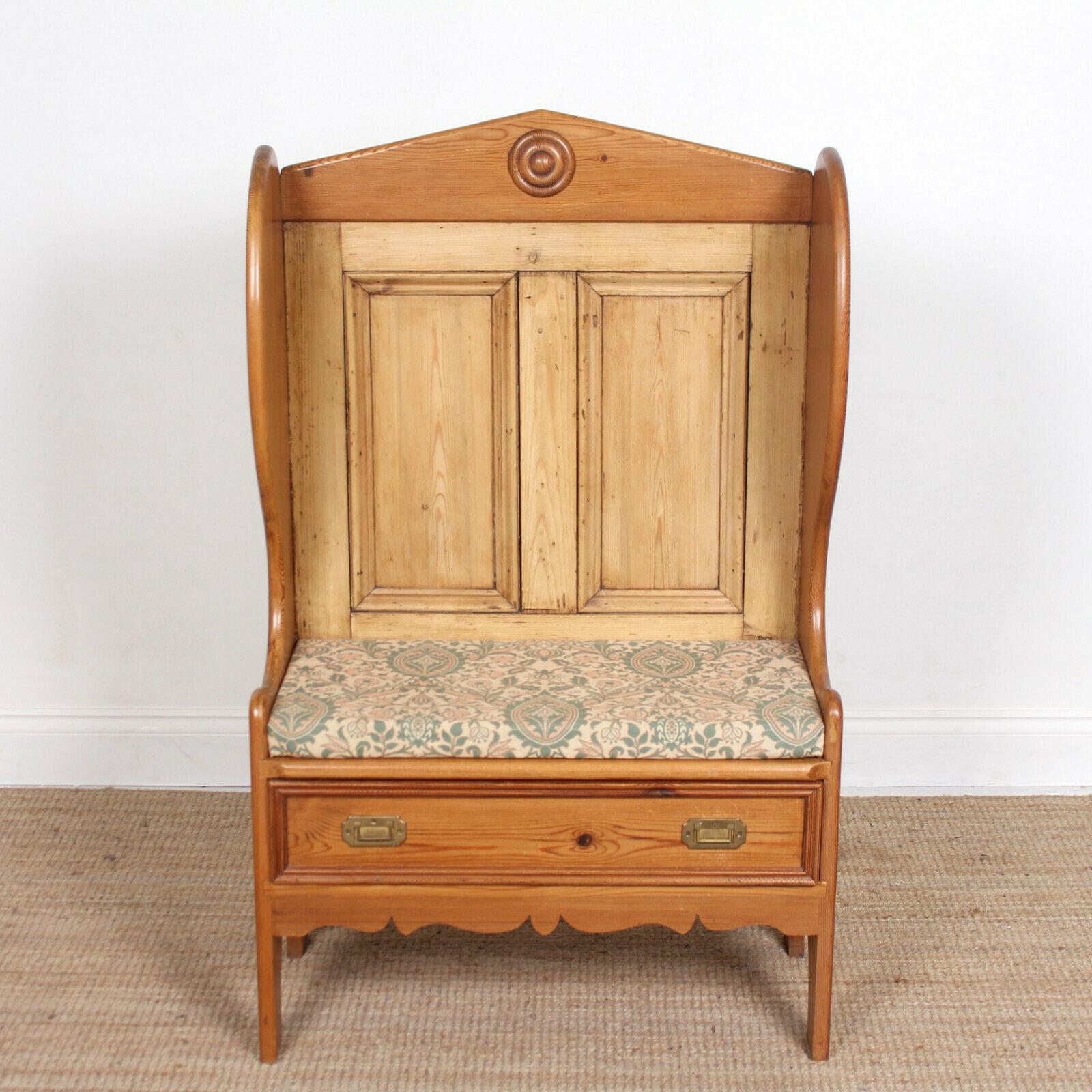 An impressive carved and paneled pine settle in the Arts & Crafts manner.

The paneled upstand with carved motif and supports above a removable upholstered seat and drawer with brass inset handles, dovetailed jointing and pine
