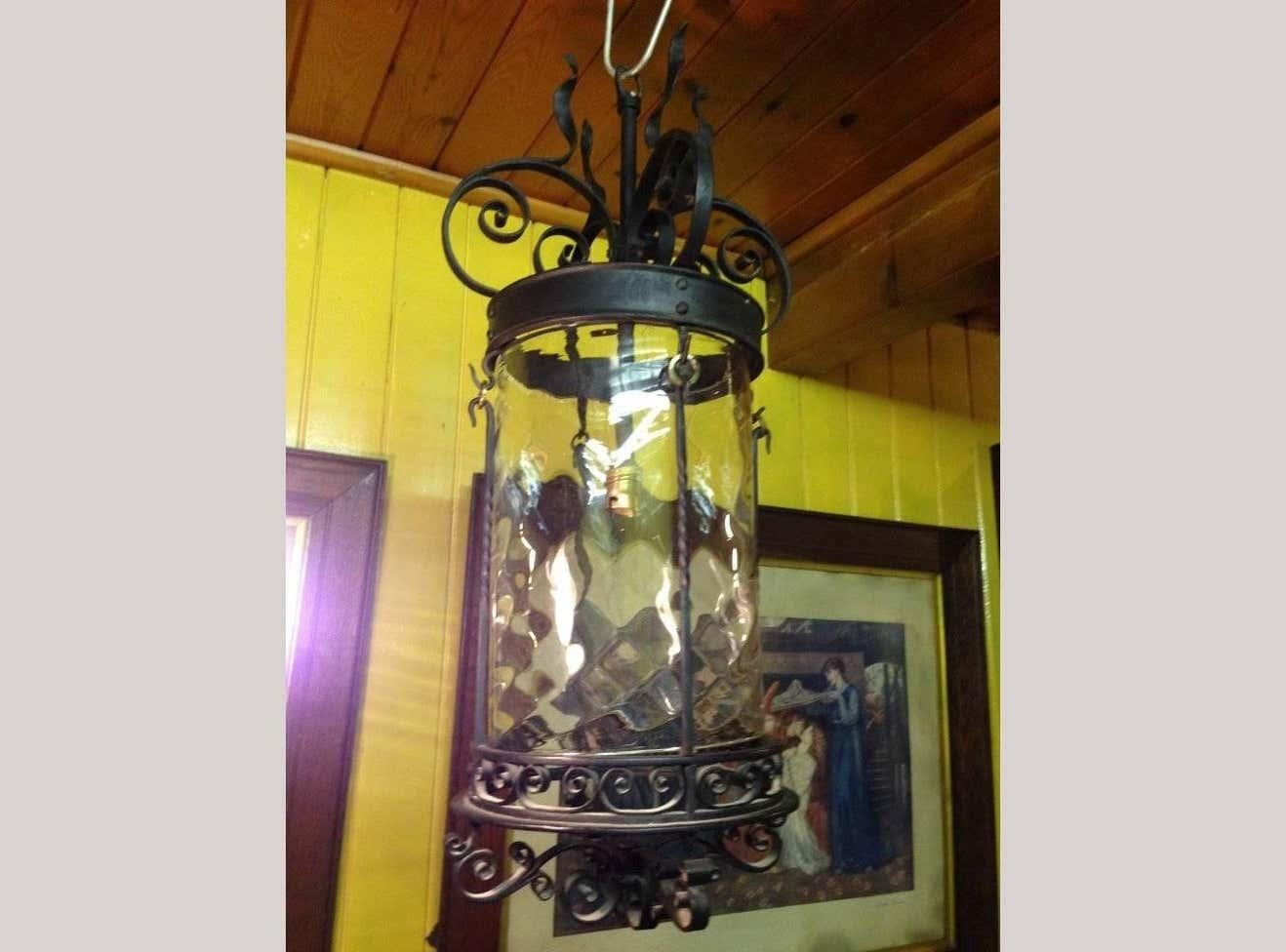 An English Arts and Crafts iron lantern in the style of the Birmingham Guild of Handicraft with flaming tendrils to the top and decorative scrollwork decoration.
Retaining the original glass liner with the undulating surface area giving off a nice