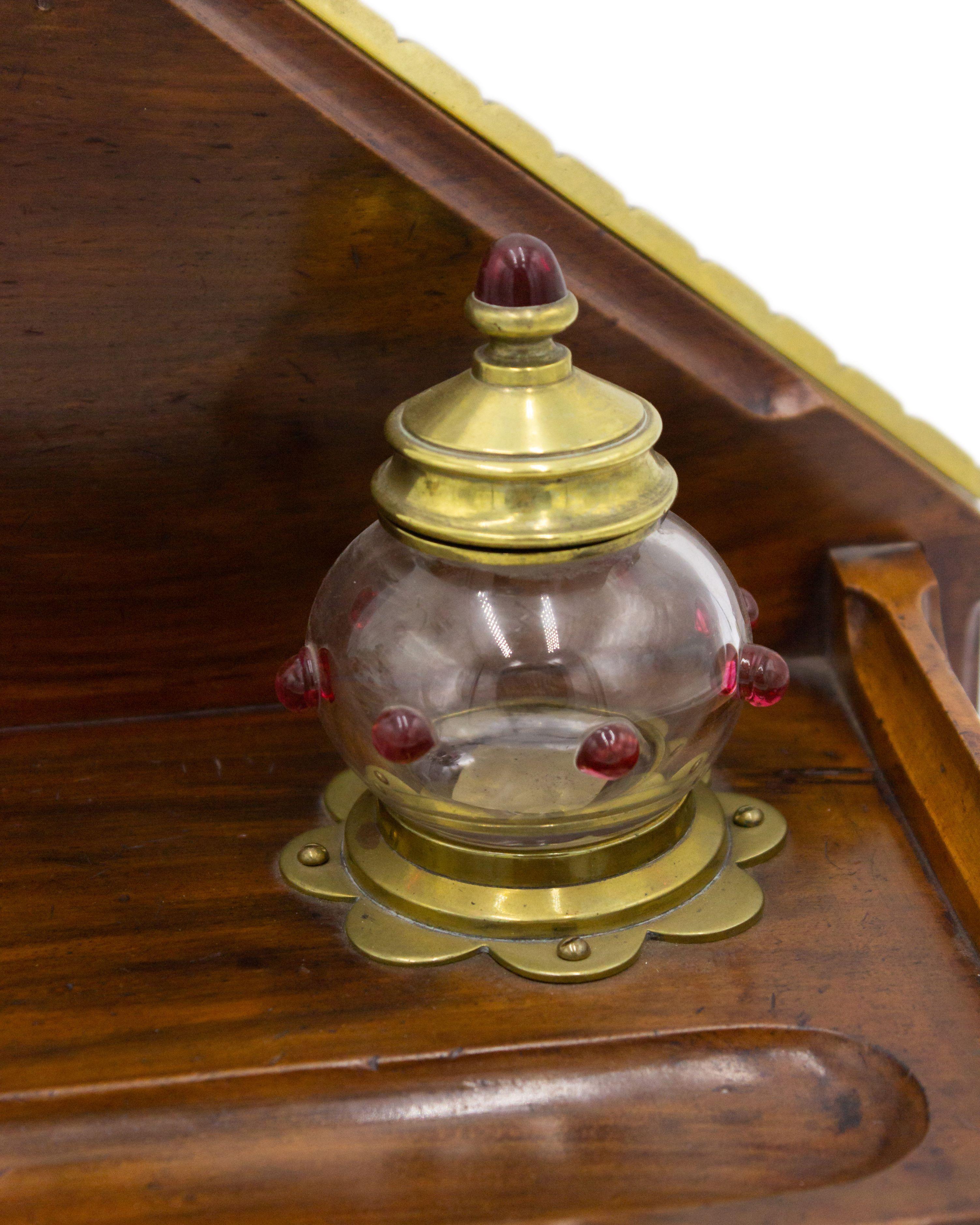 English Arts & Crafts (Gothic Revival-style) mahogany and brass trimmed double inkwell with glass jewels and drawer.
  