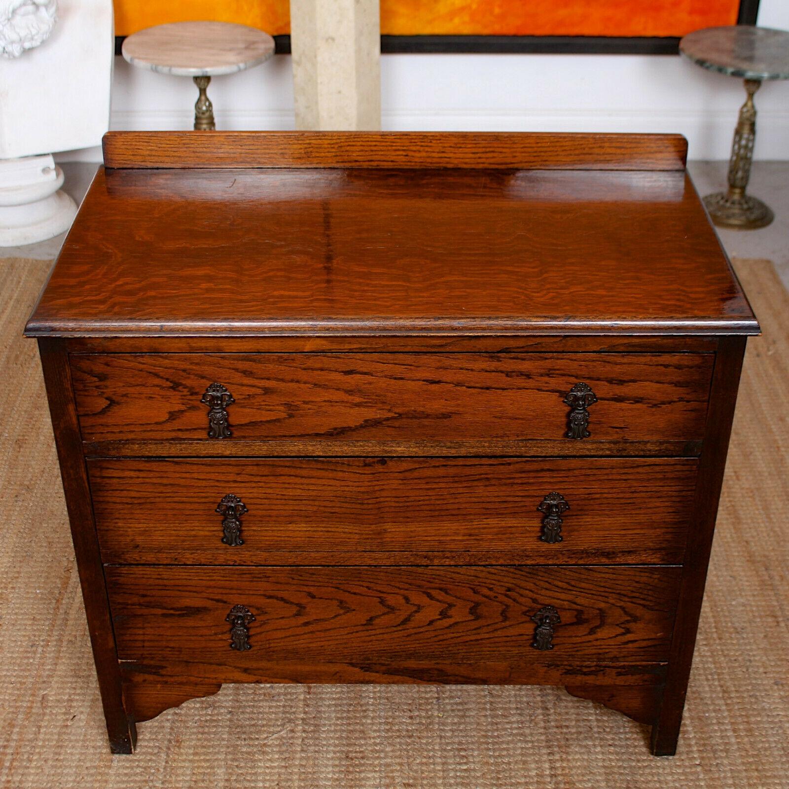 An impressive Arts & Crafts oak chest of drawers.

The oak boasting a well figured wild golden swirling and flecked grain and rich patina.

A back rail atop the chamfered edged top. Fitted three graduated long drawers with paneled interiors,