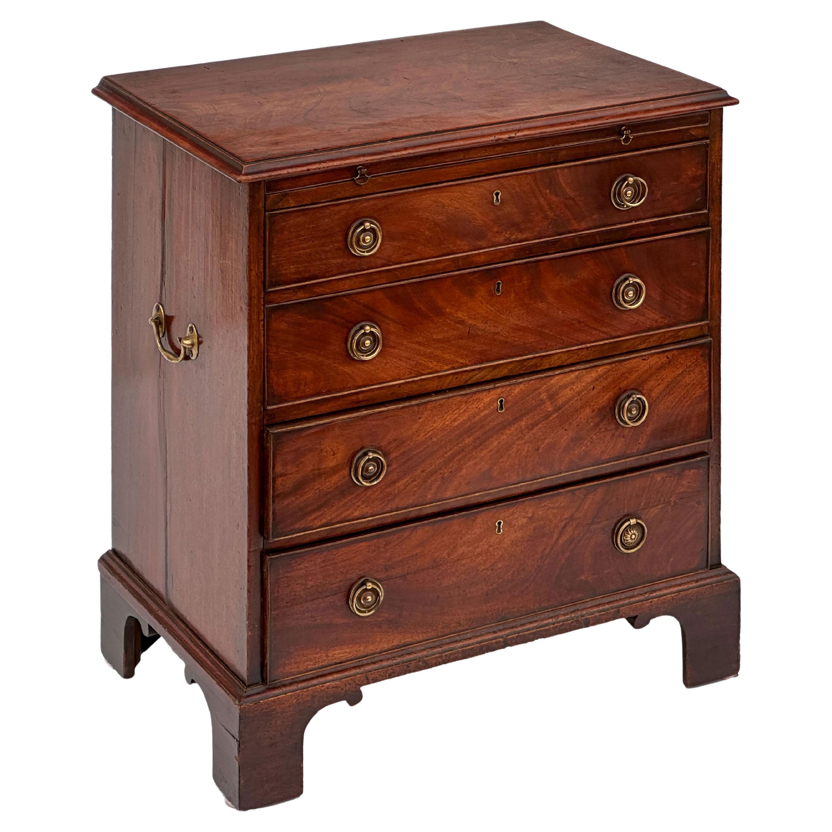 Una bella cassettiera inglese da scapolo (o cassettone) in mogano, caratterizzata da un piano in mogano modellato a fiamma su un fregio con slitta per scrivania da scapolo estraibile e quattro cassetti perlinati, tutti con belle ferramenta in ottone