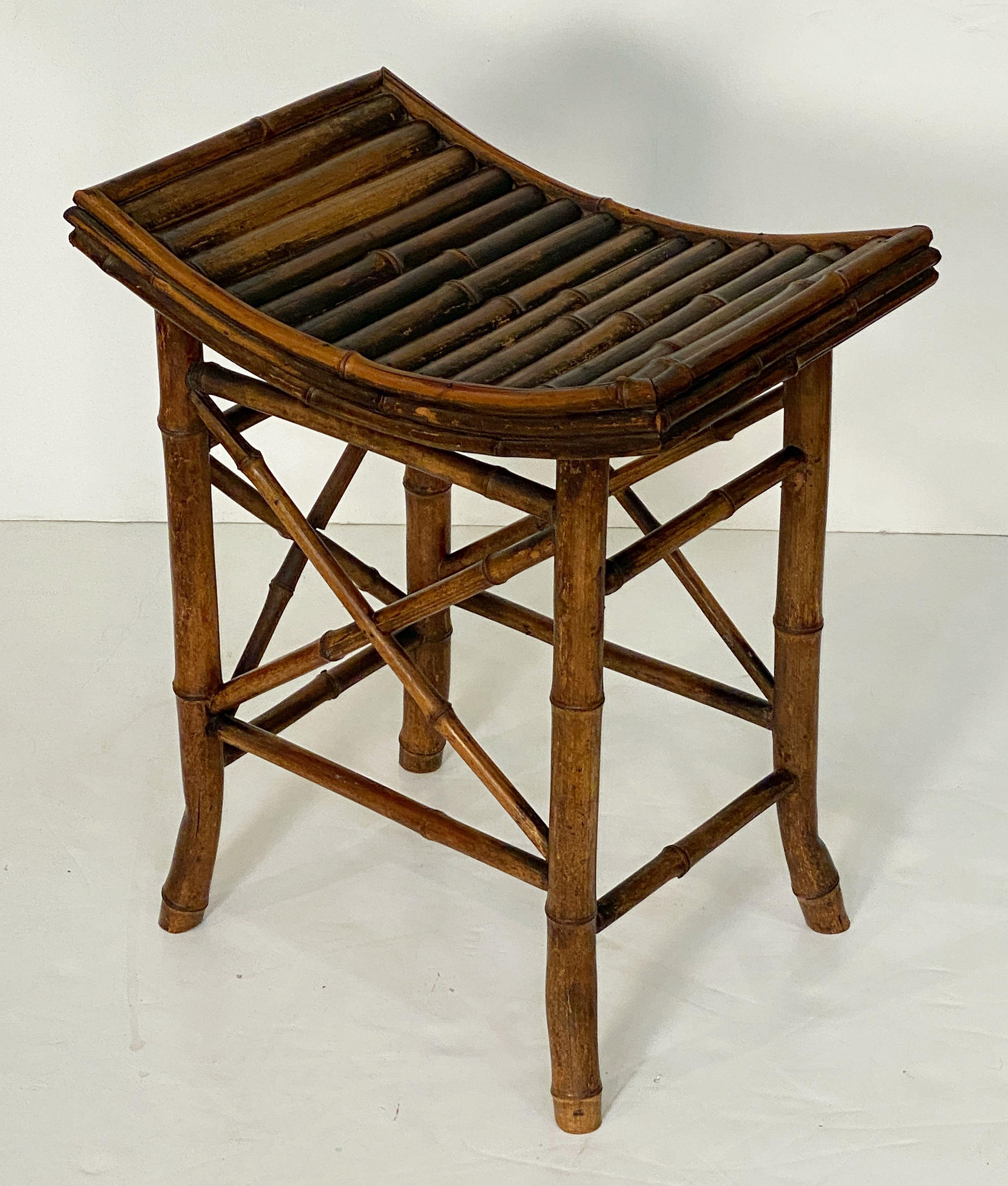 A fine English bamboo bench or stool from the Aesthetic Movement period of the late 19th century, featuring a handsome patinated finish and lovely curved rectangular saddle seat, upon a decorative four-legged stretcher base.