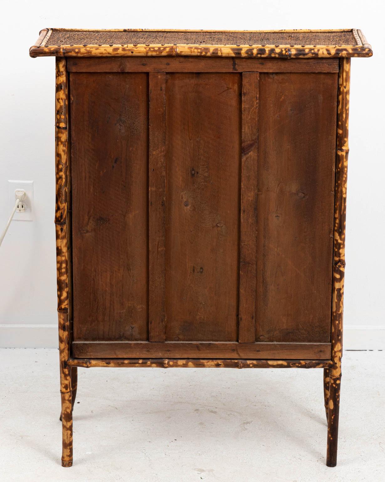 English faux tortoise petite bamboo bookcase or cabinet with glazed glass doors and three shelves, circa late 1800s. Please note of wear consistent with age including a small patch on side where repaired. Made in England.