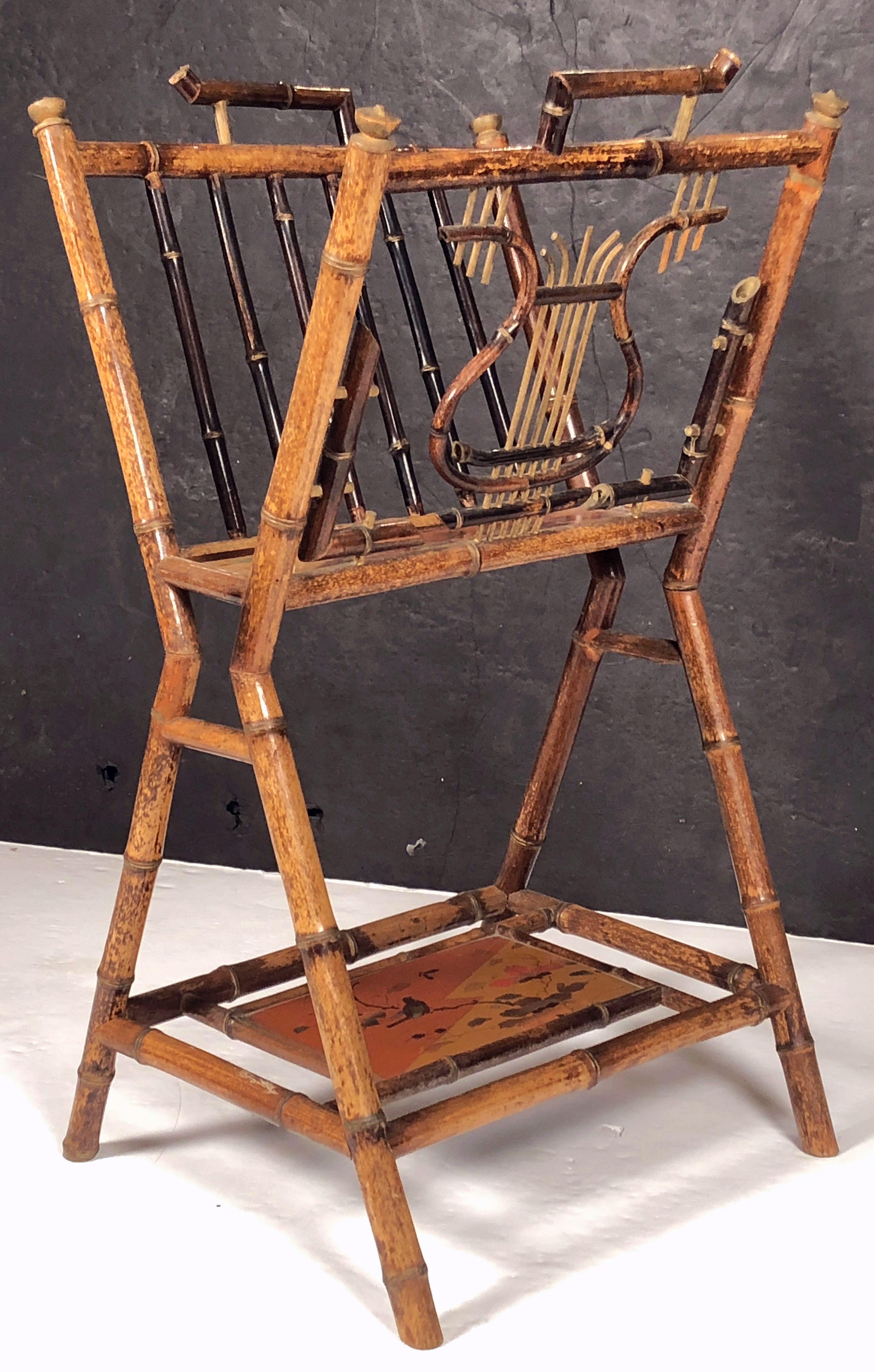 A fine English bamboo Canterbury music stand or magazine rack featuring a bamboo stand with a lyre design in bamboo, with lacquered chinoisierie panel under-tier and stretcher base, and decorative caps.