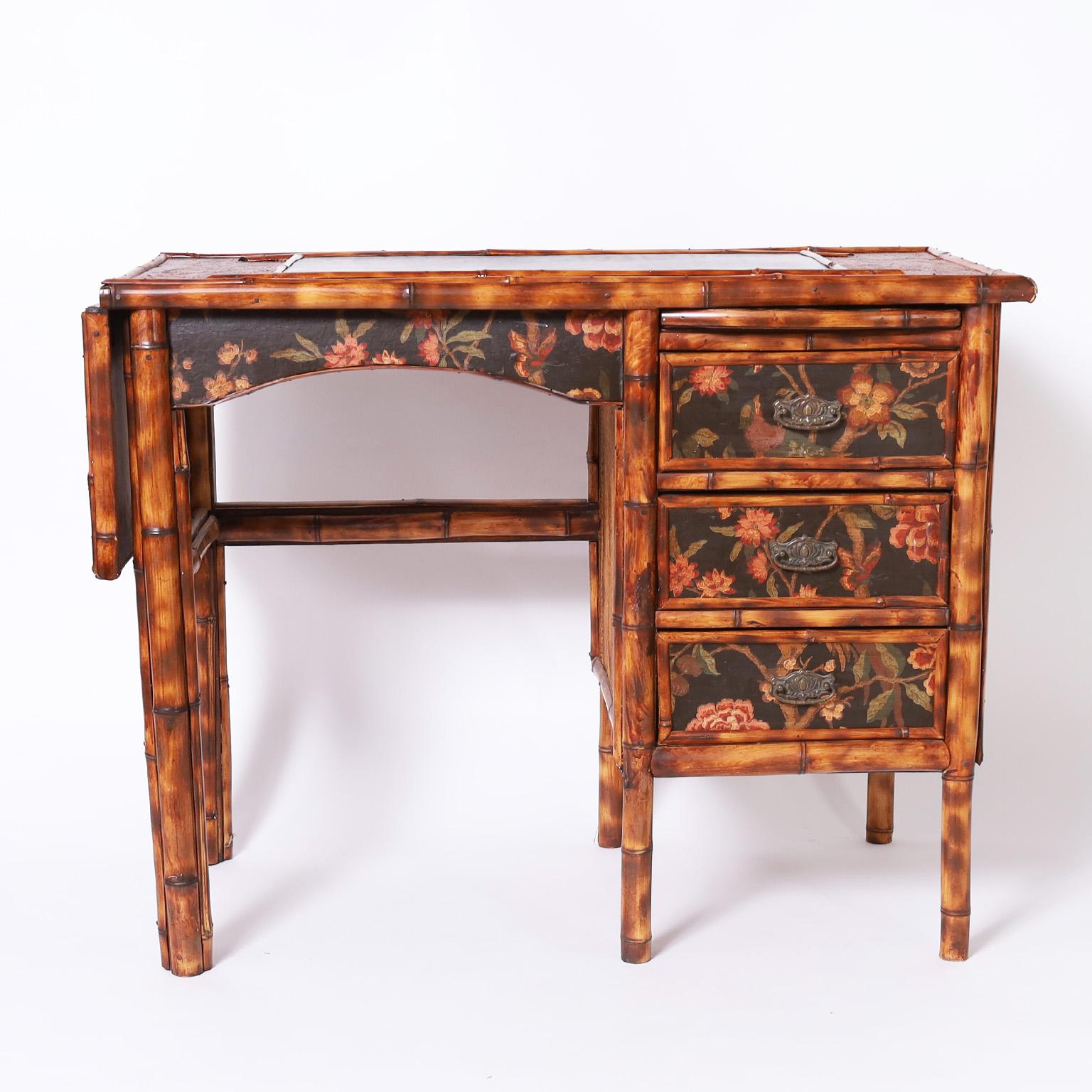 Charming 19th century three drawer desk featuring leather panels on top, foldout writing shelf, grasscloth panels on the top and side and floral decoupaged drawer fronts and pull out tray as only the English can do. 

Extended width: 47
