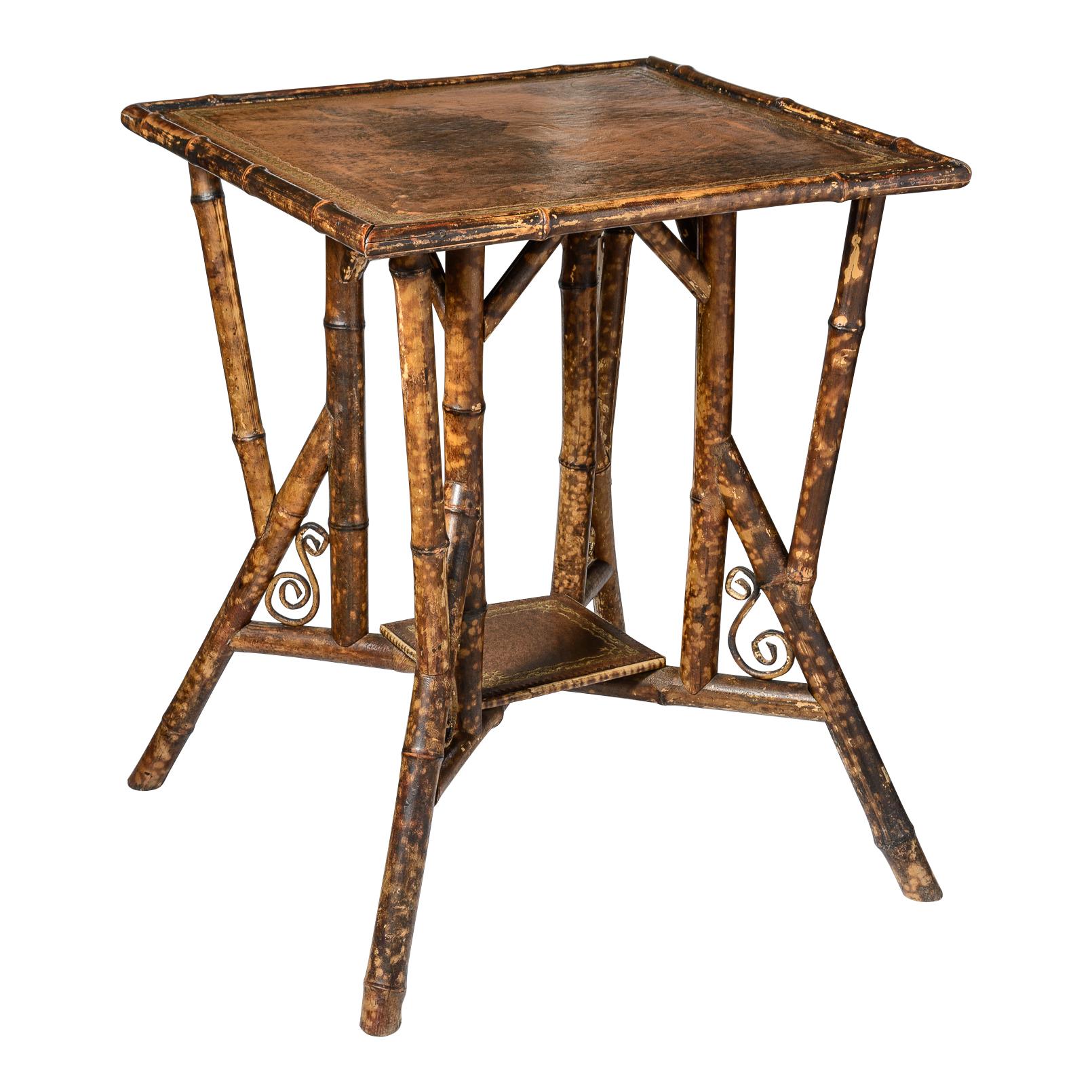 
This late 19th C. English Bamboo table is from the  Aesthetic Movement period.
This table has the beautiful Tortoiseshell bamboo color.
This square side table top is covered in a beautiful embossed tooled leather.
The second tier has also tooled