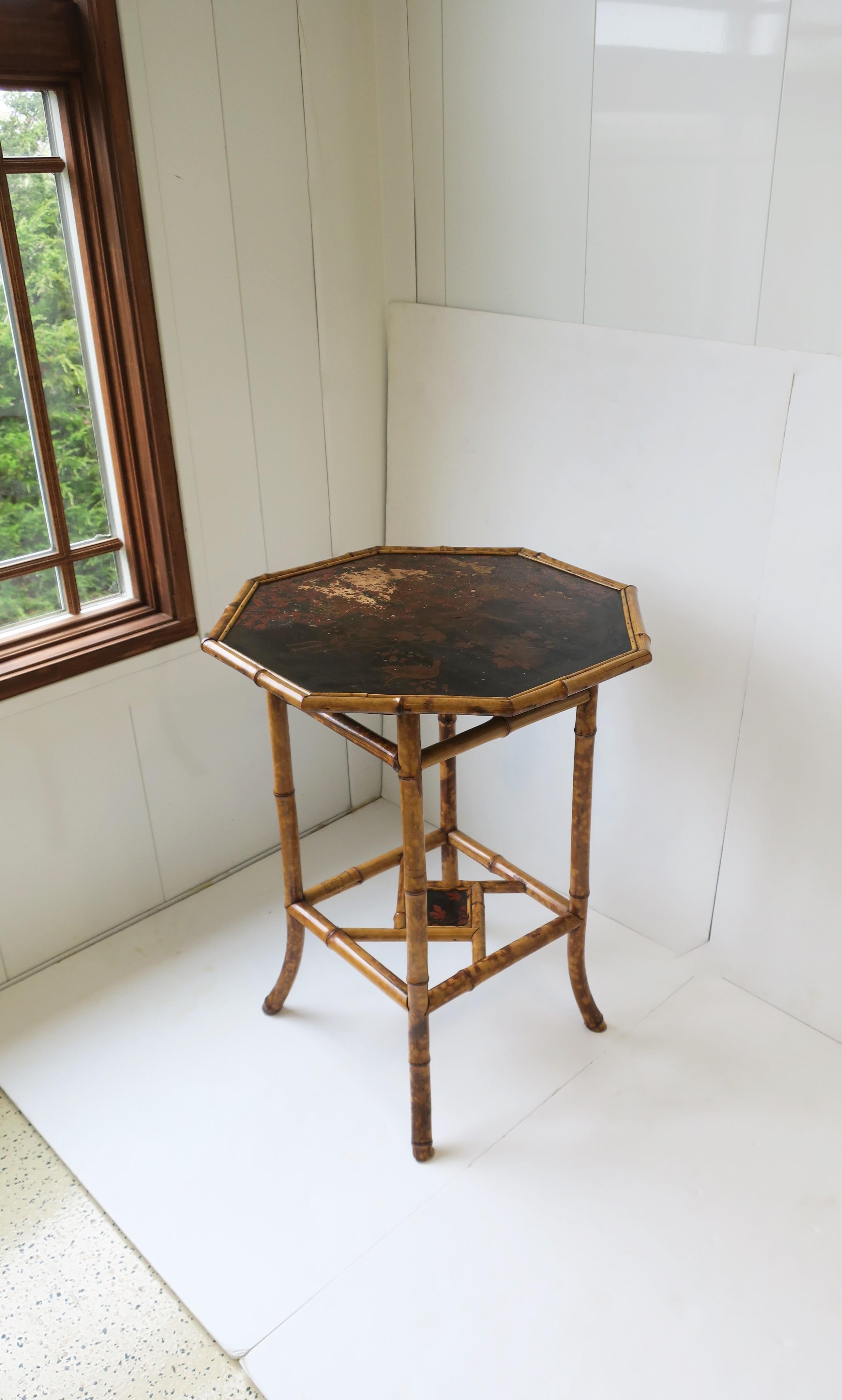 An English bamboo end table with an octagonal japanned top of birds and leaves, finished with a stretcher base, circa late 19th century, England. Dimensions: 22.25