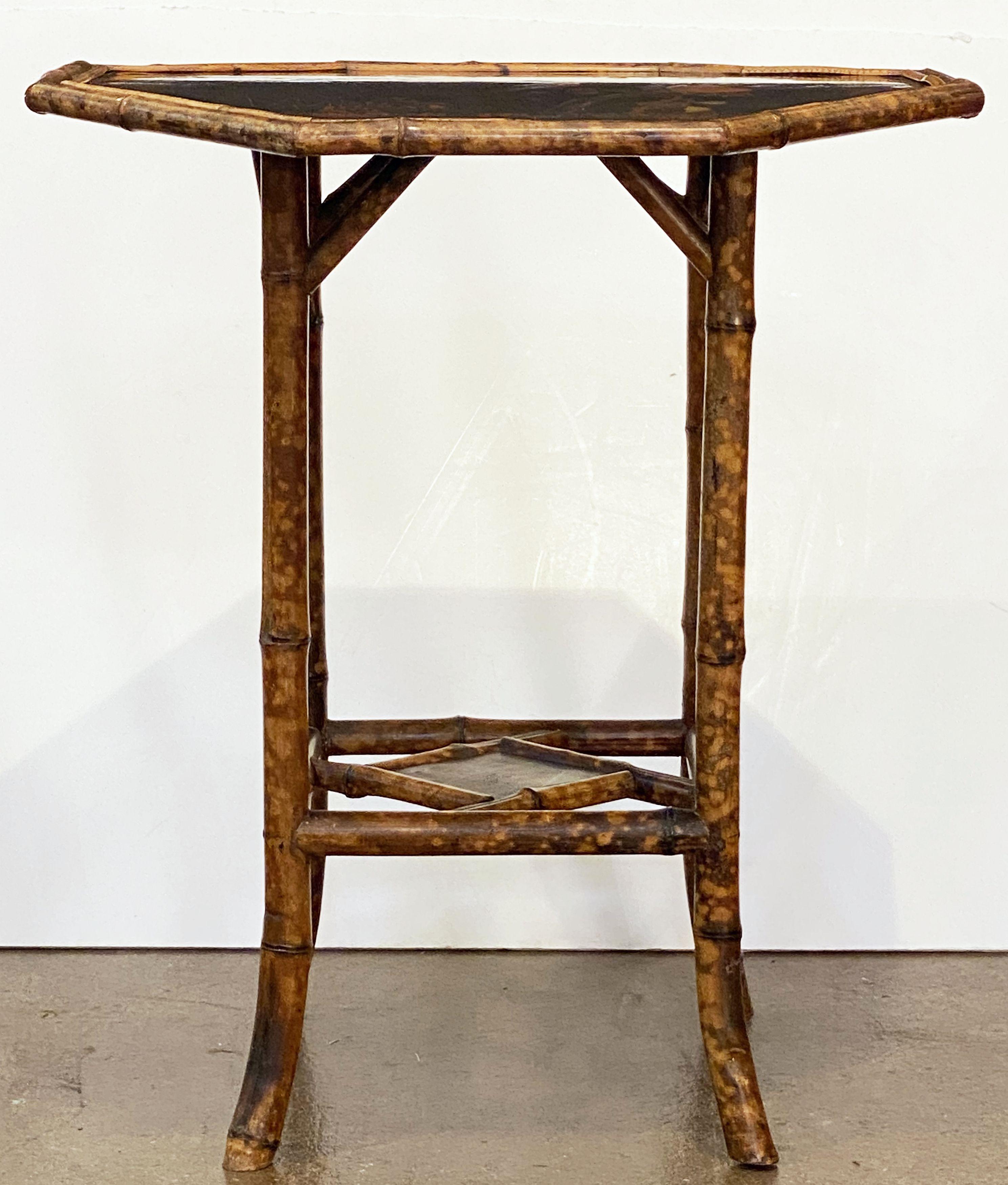 A fine English bamboo table (side or occasional), c.1870-1910, featuring an octagonal top with Japan lacquered chinoiserie design, over a stretcher base with diamond-shaped lacquered panel and ornamental fretwork running diagonally at each corner.