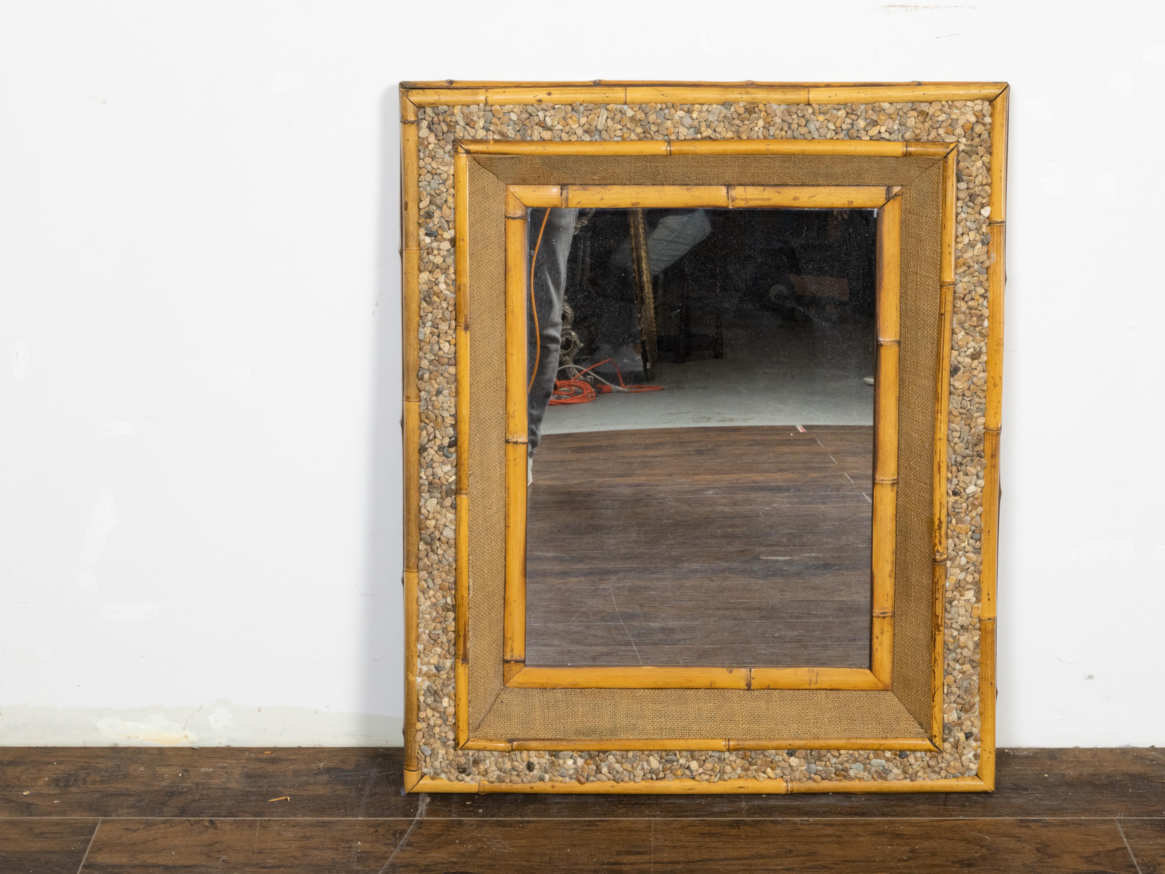 An English vintage rectangular bamboo mirror from the mid-20th century, with rock and burlap décor. Created in England during the Midcentury period, this unusual mirror attracts the attention with its rectangular frame alternating bamboo, rocks and