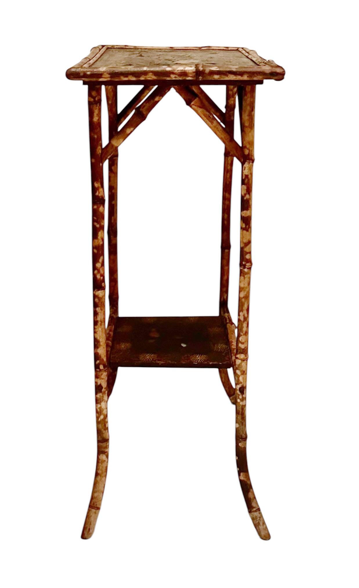 An English bamboo side table dating to the early 1900s. The top and lower shelf are decorated with painted scenes of birds, vines, and flowers, adding charm and character to the natural bamboo frame.

The surface of the top shows wear consistent