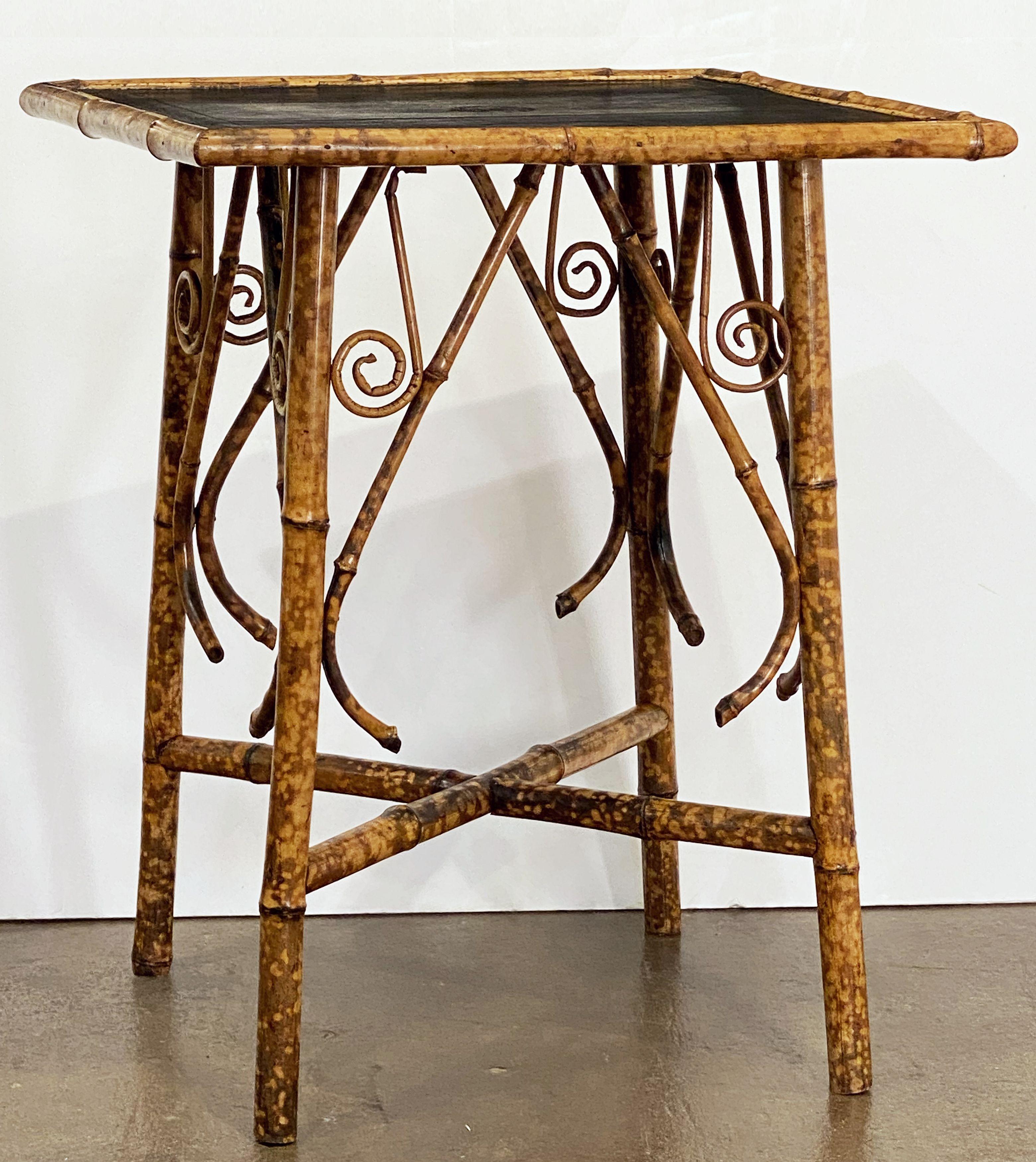 A fine English bamboo table from the Aesthetic Movement period, c.1870-1910, featuring a square top with embossed leather and bamboo accents over a four-legged stretcher frame of bamboo.
