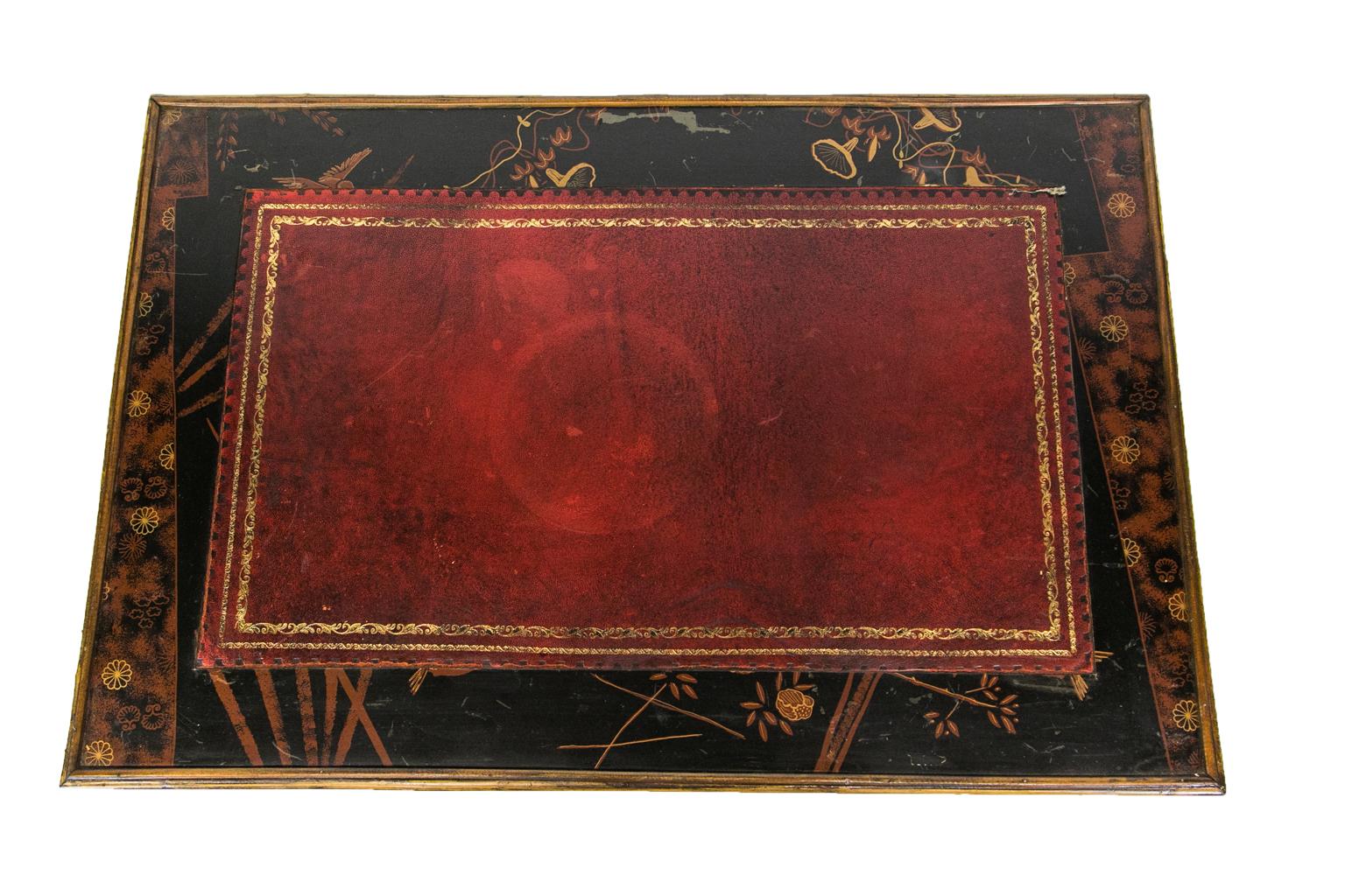 English bamboo writing table has a lacquer drawer front, sides, and top, which frame the red leather gold tooled center. The base has bamboo stretchers that frame a square lacquer panel.
 