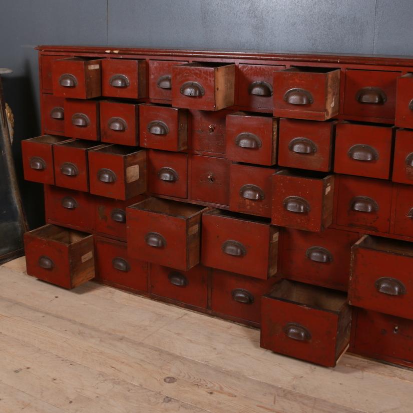 Amazing 19th century original red painted seed merchant drawers, 1860.

Dimensions
110 inches (279 cms) wide
12 inches (30 cms) deep
38.5 inches (98 cms) high.

   