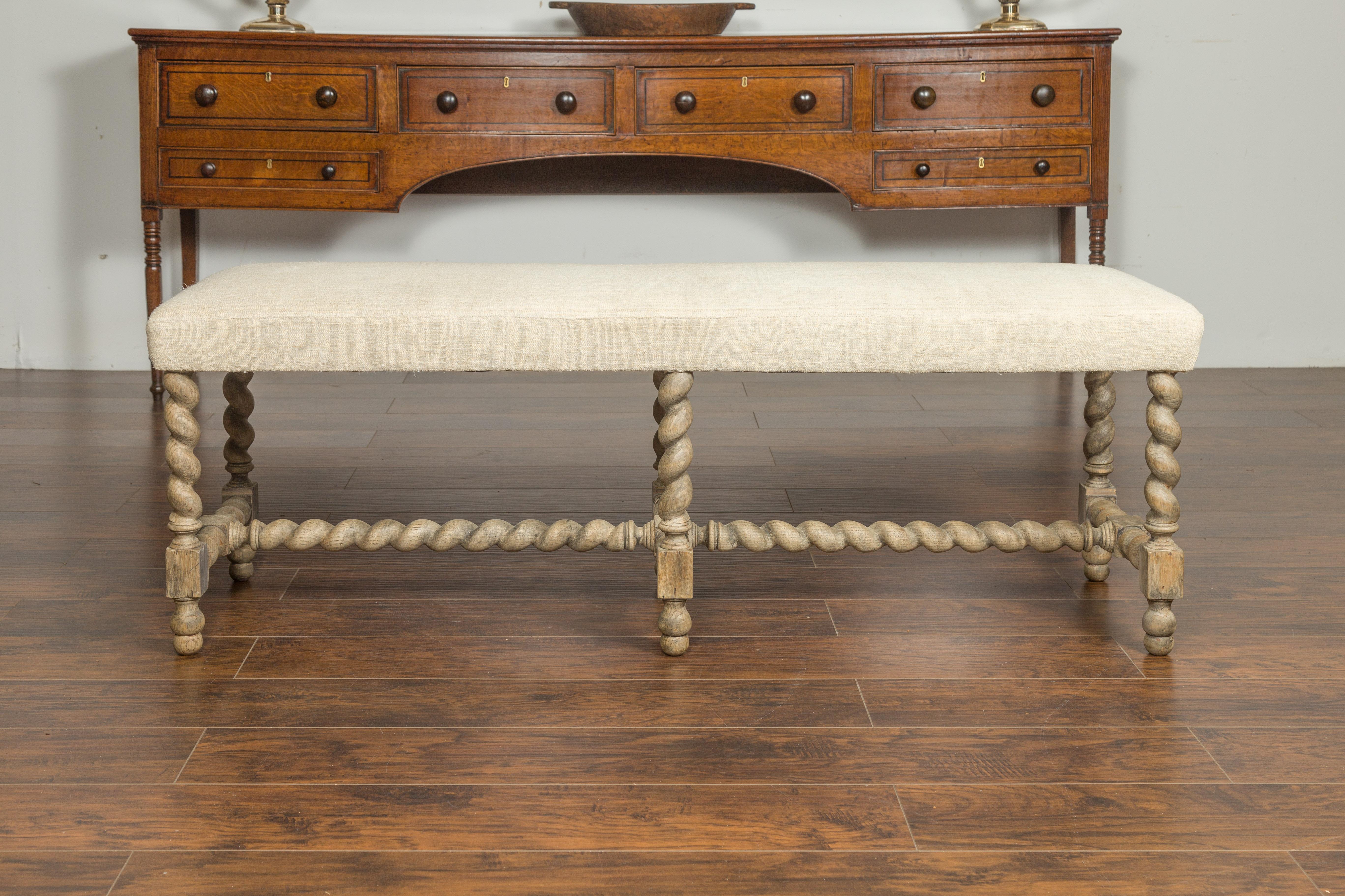 An English barley twist bleached wood bench from the late 19th century, with cross stretcher and new upholstery. Created in England during the last quarter of the 19th century, this bleached wooden bench features a long rectangular seat newly