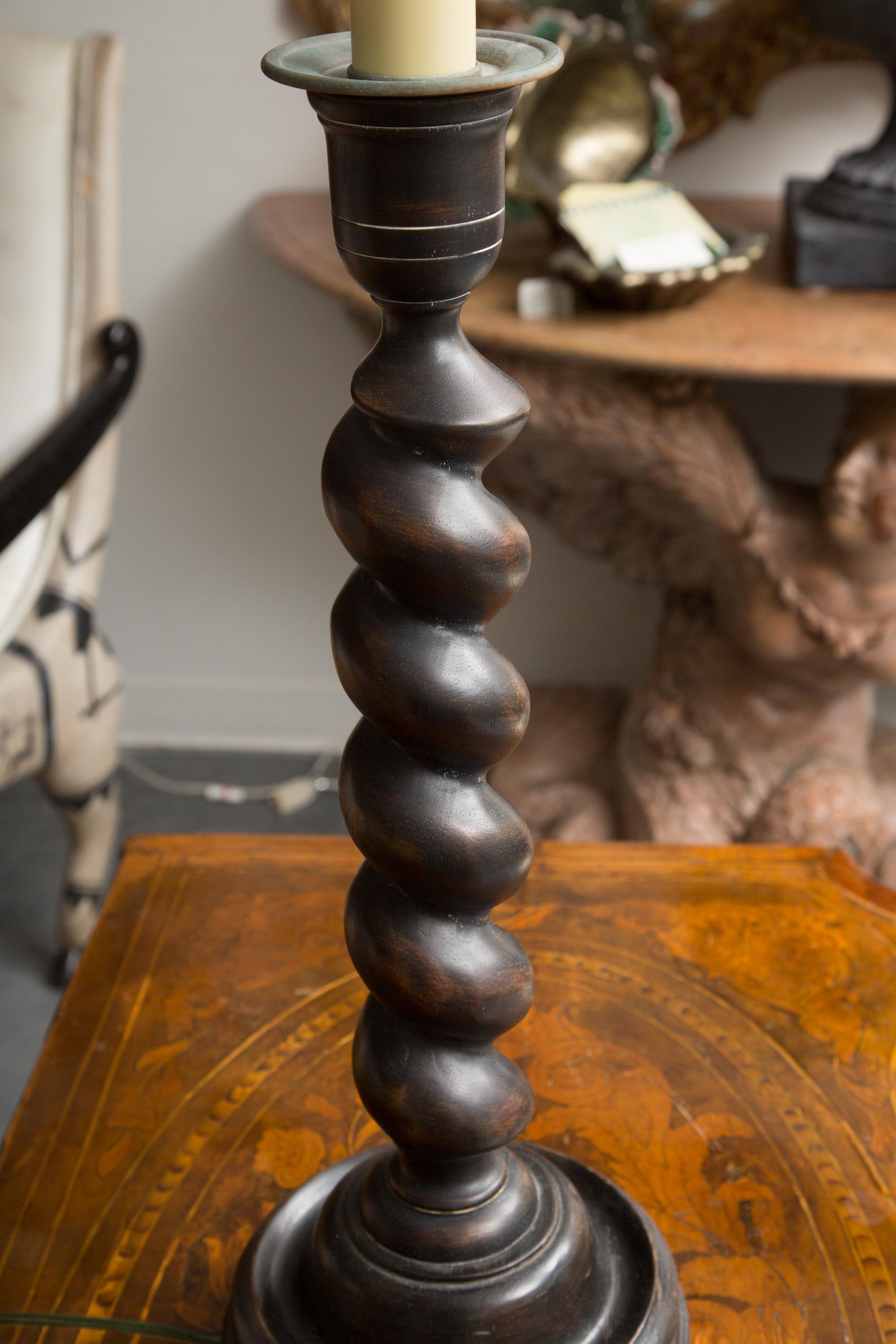 These are a classic pair of 'old world' barley twist tall candlesticks made as table lamps. The wooded twisted candle sticks with a metal bobeche are mounted on a metal square base patinated to match the candle stick. They are electrified with a