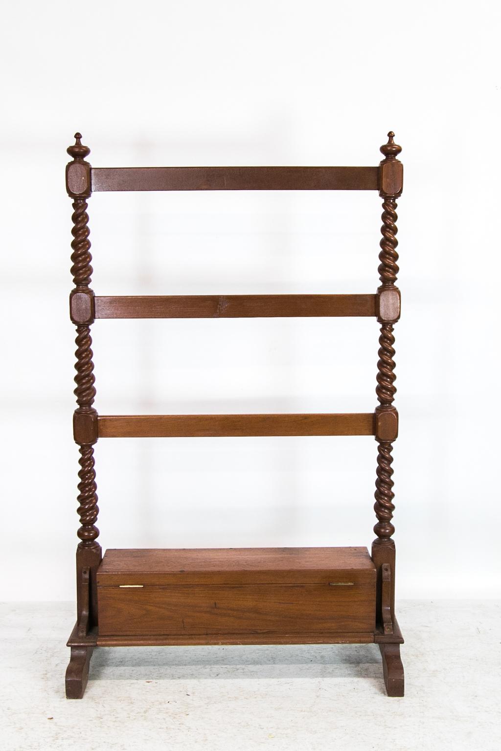 This rack/chest has three cross rails supported by bold barley twist columns. It has a lift top box that rests on a platform base which is supported by four shaped feet.