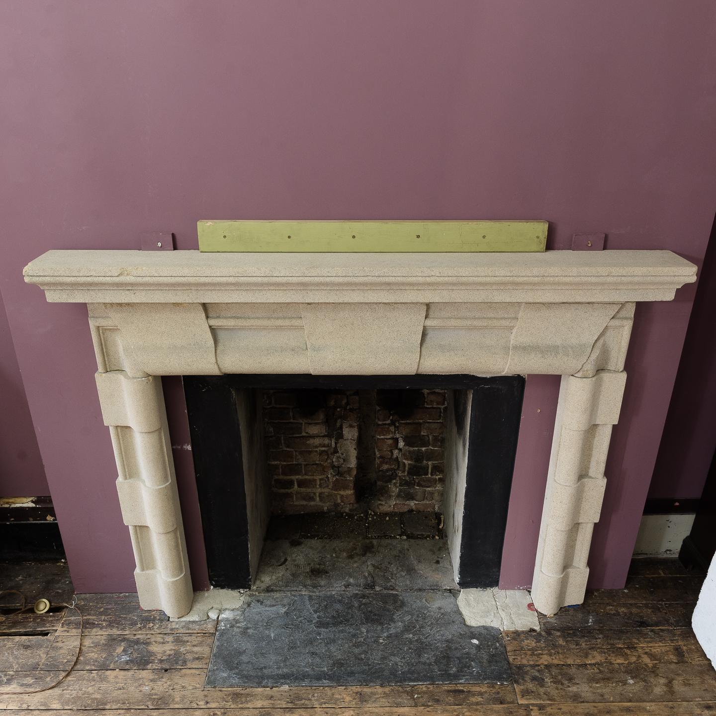 English Baroque style stone fireplace, the rectangular shelf above quoin embellished bolection moulded frieze and jambs, on square footblocks.
  