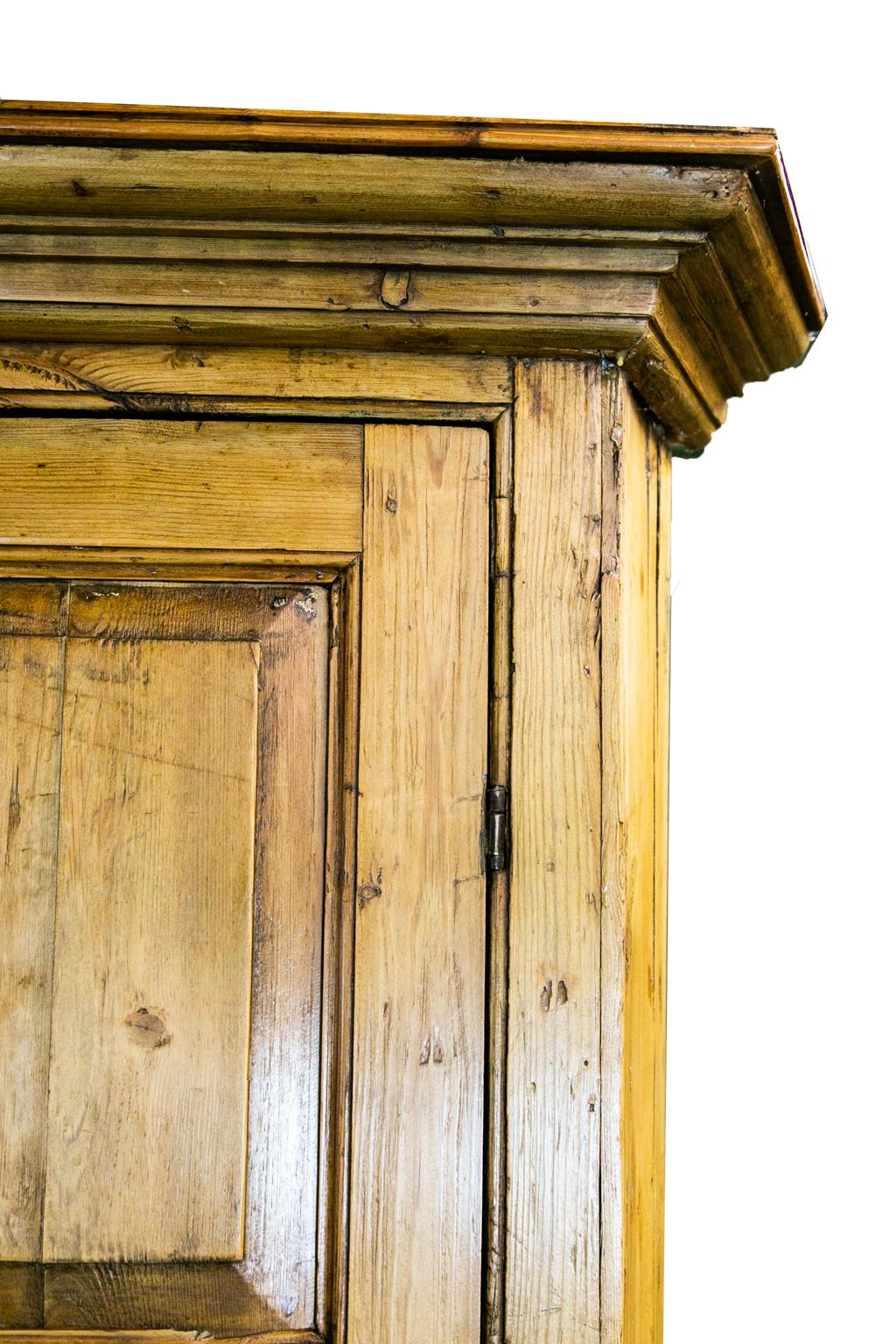 Der englische Eckschrank aus Kiefernholz hat in der Mitte zwischen Ober- und Unterteil eine ausziehbare Rutsche. Das Oberteil hat geformte Ablagen, die von einem gewölbten Rahmen umgeben sind. Die Türen haben klassische, erhabene Füllungen, das blau