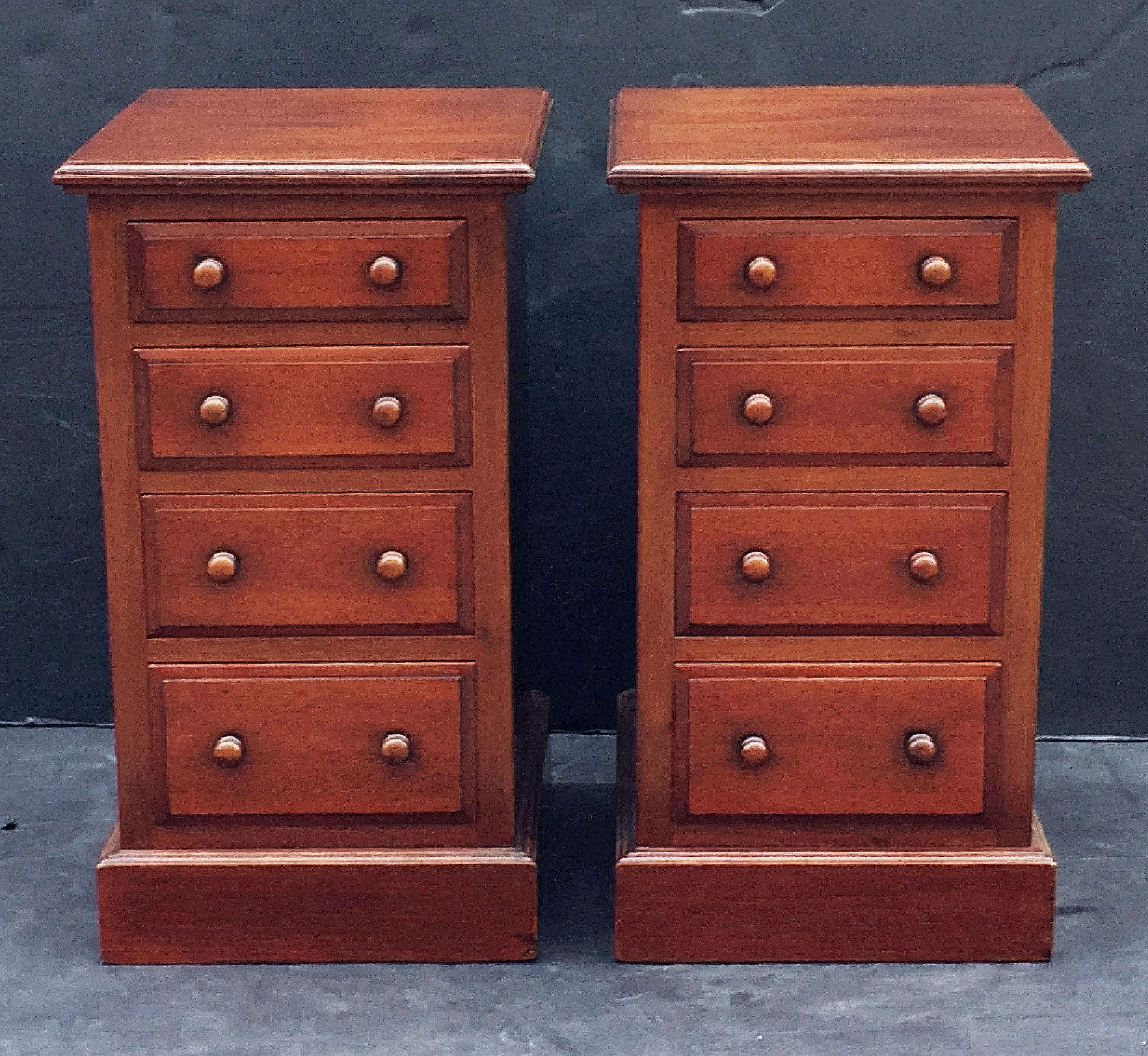 A handsome pair of English bedside chests or cabinet night stands of mahogany each chest with a molded top over a frieze of four drawers of ascending size (top to bottom), each drawer with wood knobs, and set upon a plinth base.

Priced as a pair