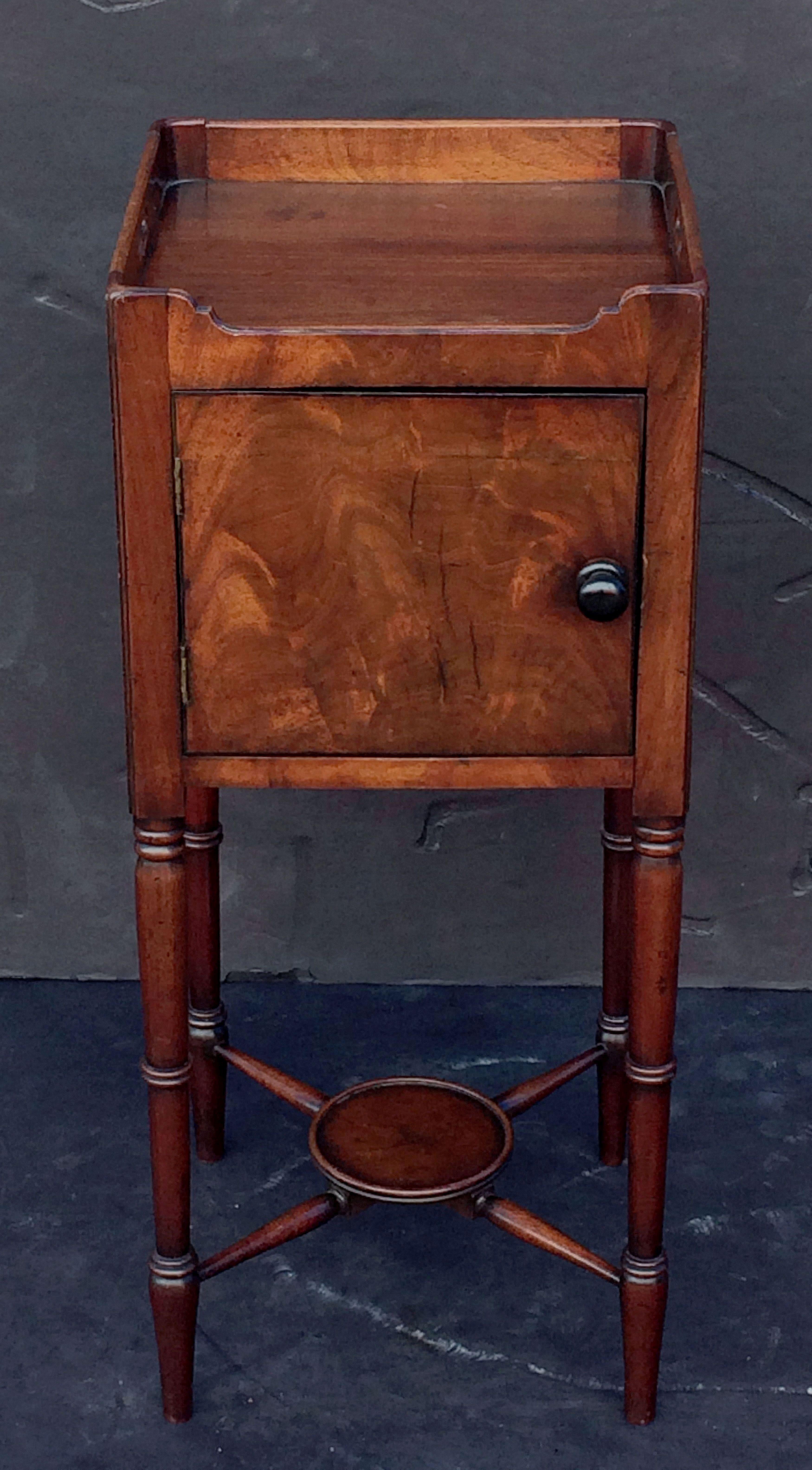 A handsome English nightstand or end (side) table of mahogany, from the William IV era, with molded top with gallery, over a cupboard frieze with door, set upon four turned legs with a stretcher support.

Dimensions: H 33 inches x W 14 1/4 inches