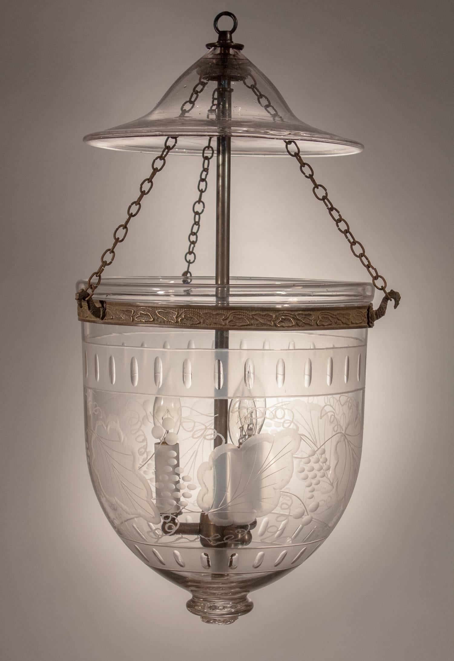 An exceptional bell jar lantern with its original etched smoke bell and brass details. This medium-sized hall lantern is distinctively decorated with a leaf and berry motif bounded by frosted banding at top and bottom. The light has been newly