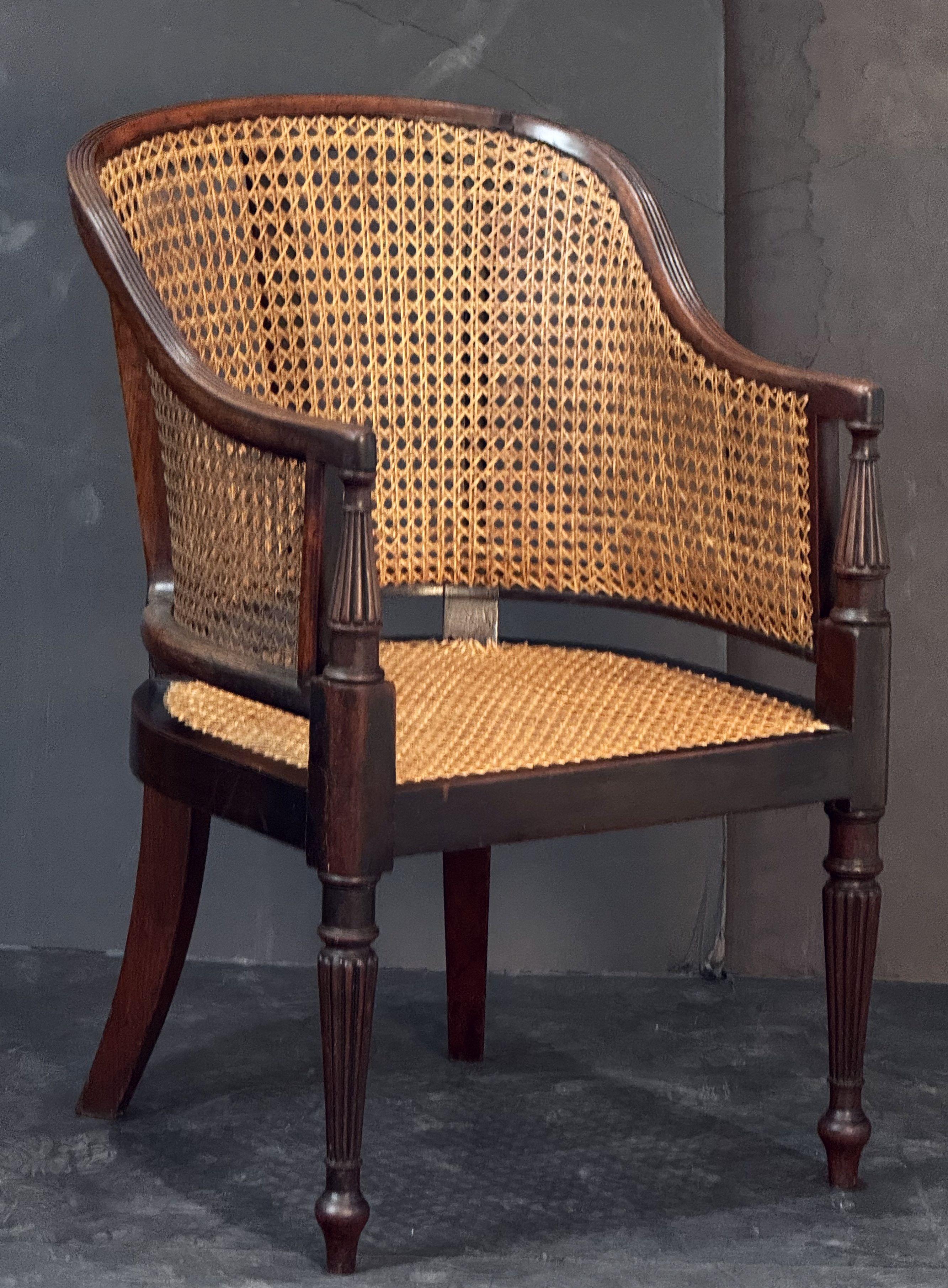 Una bella e comoda poltrona bergère o sedia da biblioteca inglese in mogano scanalato del periodo della Reggenza, caratterizzata da uno schienale e braccioli classici ed elegantemente torniti ad arco - con schienale, fianchi e sedile scanalati - e