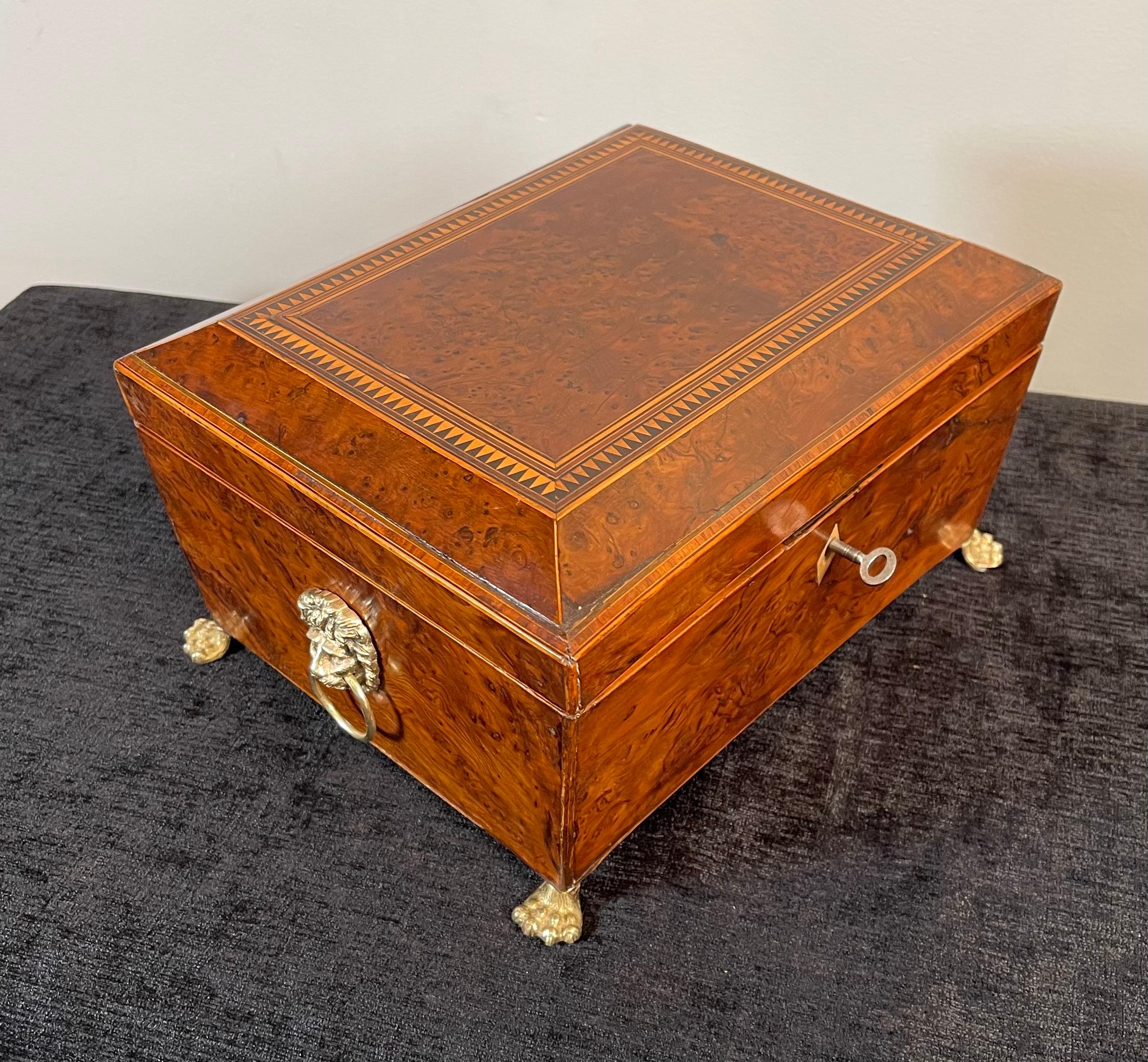 Regency birdseye maple sewing box with lions heads handles on each side & lions hairy paw feet with a key.
